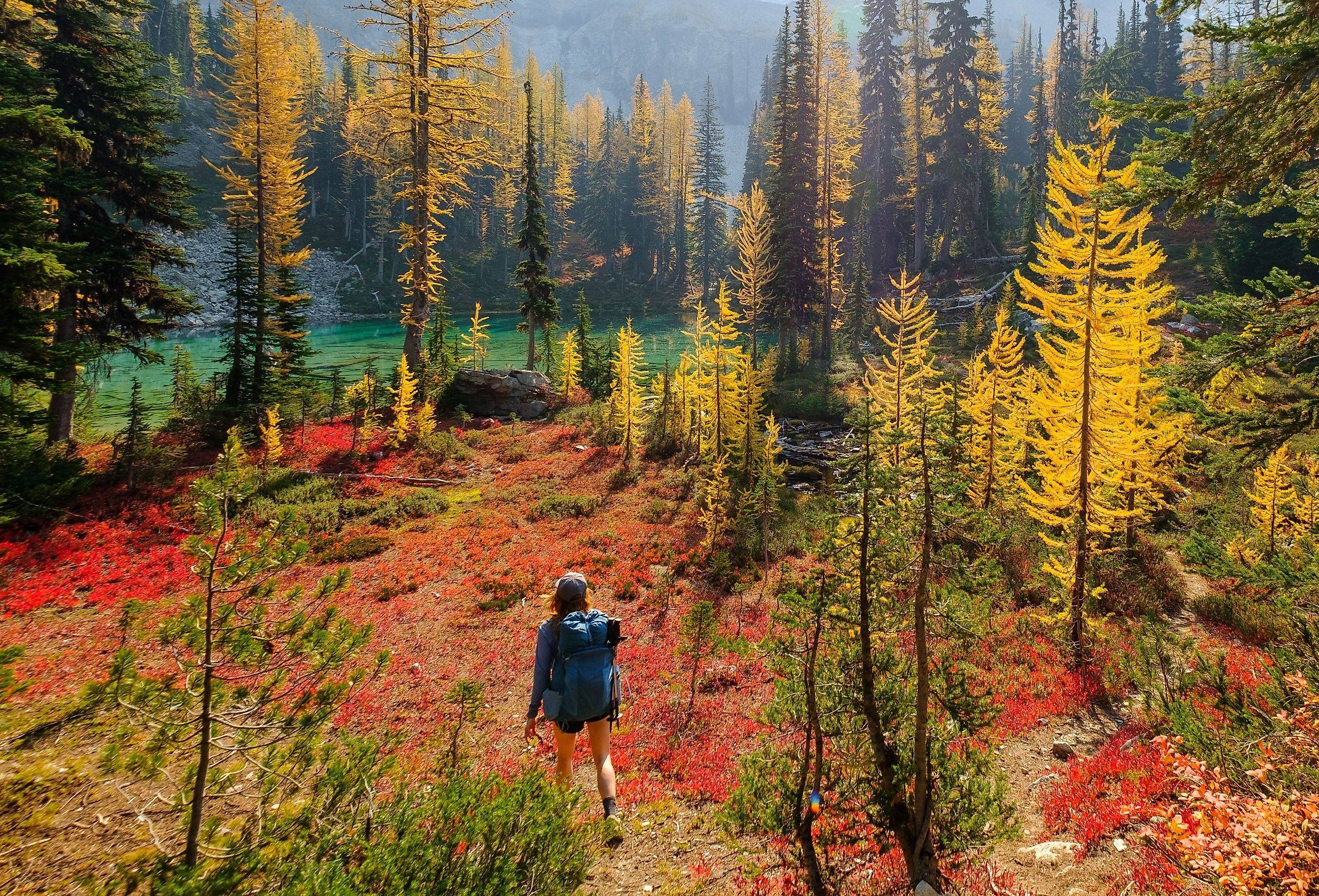 Woman hiking through the forested Cascade Mountains towards Lake Chelan, Washington.