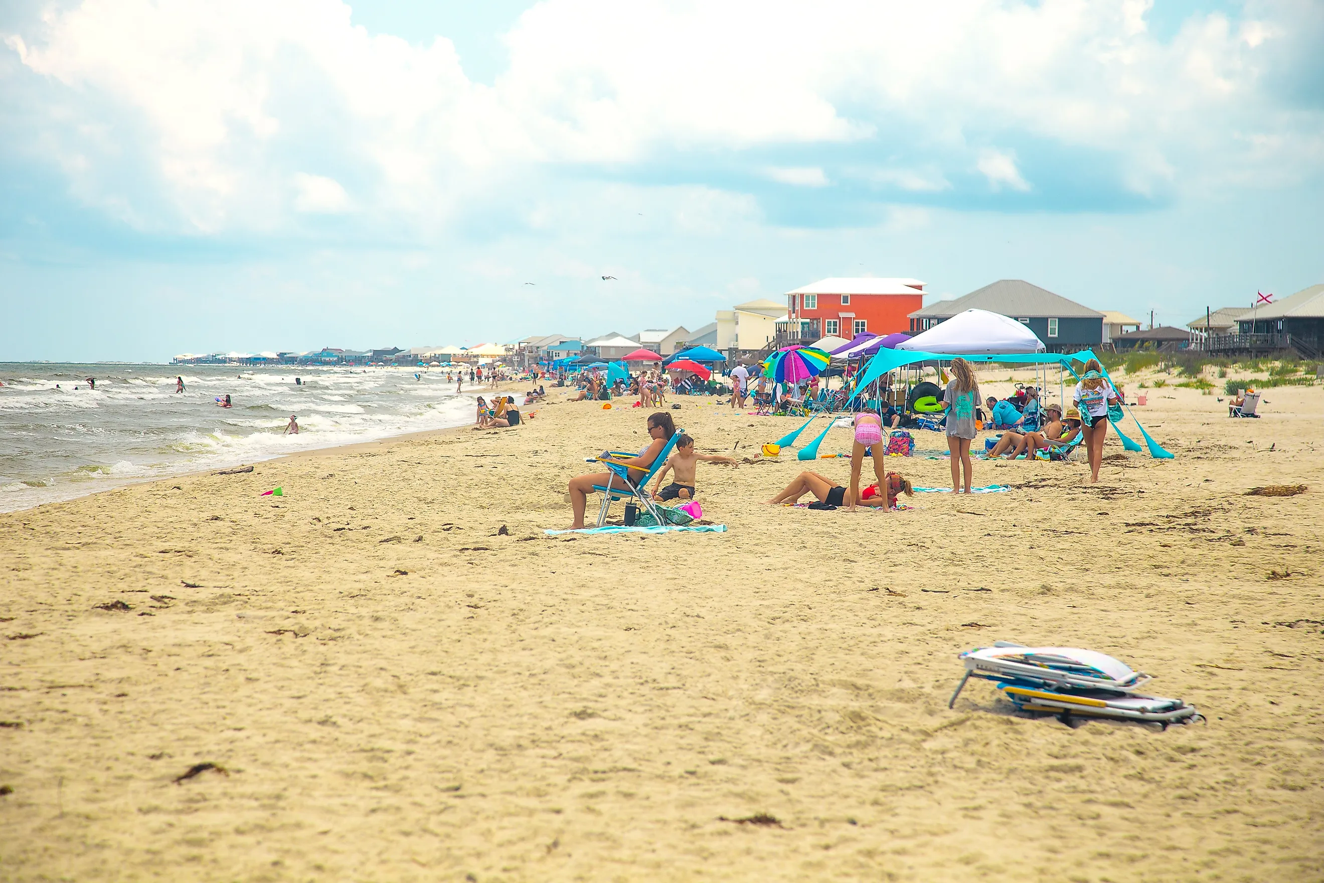 People enjoying a a busy summer beach day in Dauphin Island, Alabama. Image credit: HarrisonJeffs / Shutterstock.com
