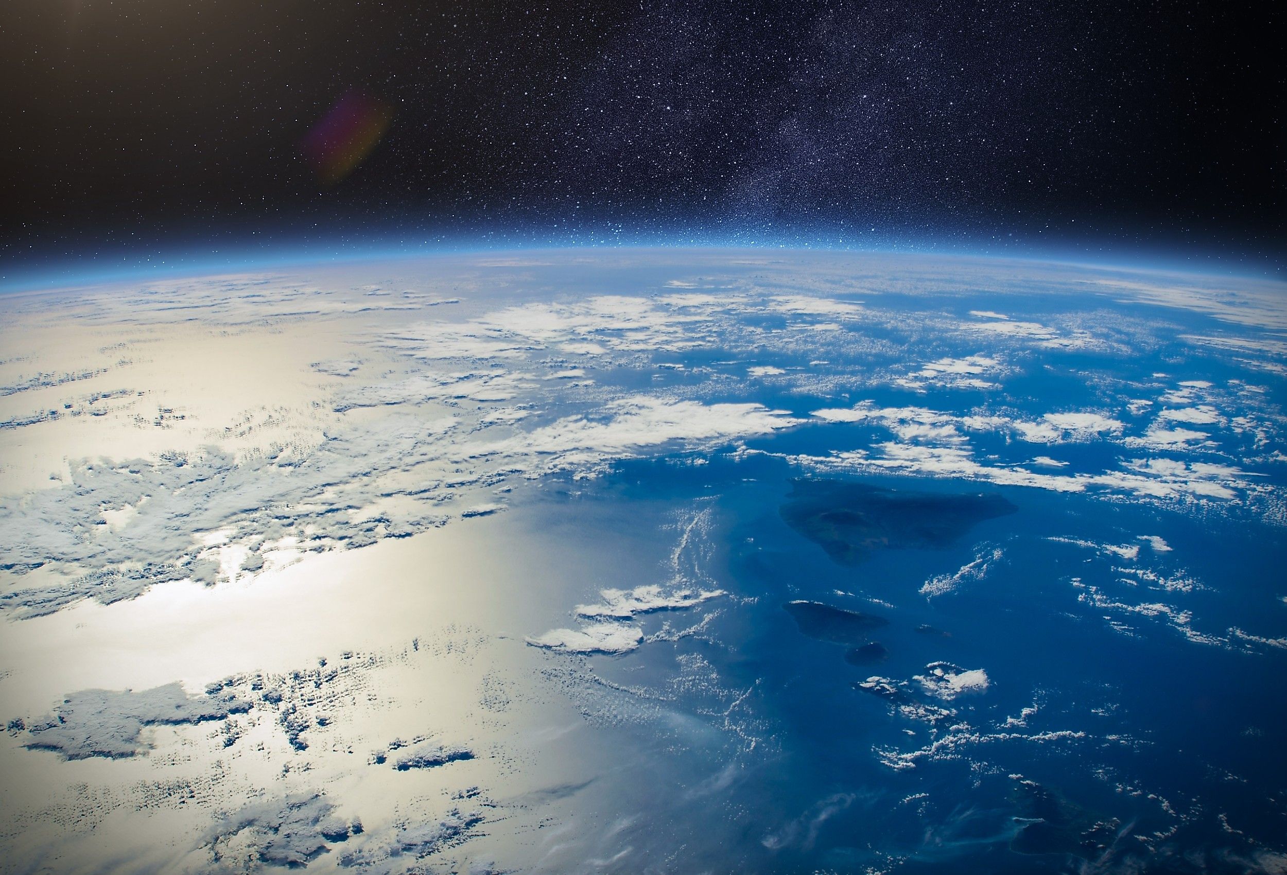 Amazing planet Earth in outer space and the sun's glint beams off the ocean.