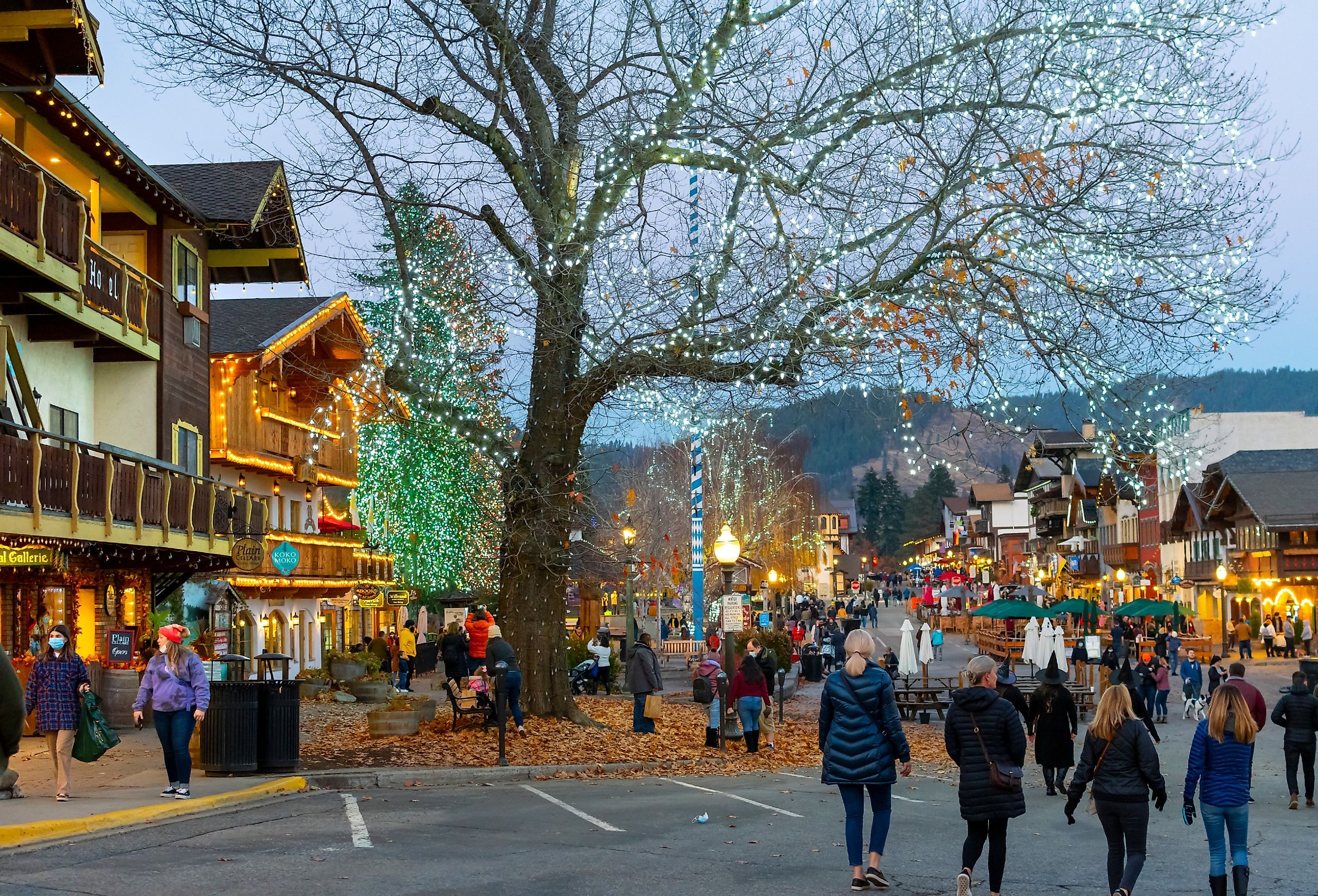 Tourists wander the main street of the Bavarian themed town of Leavenworth with shops illuminated and holiday lights on the trees.