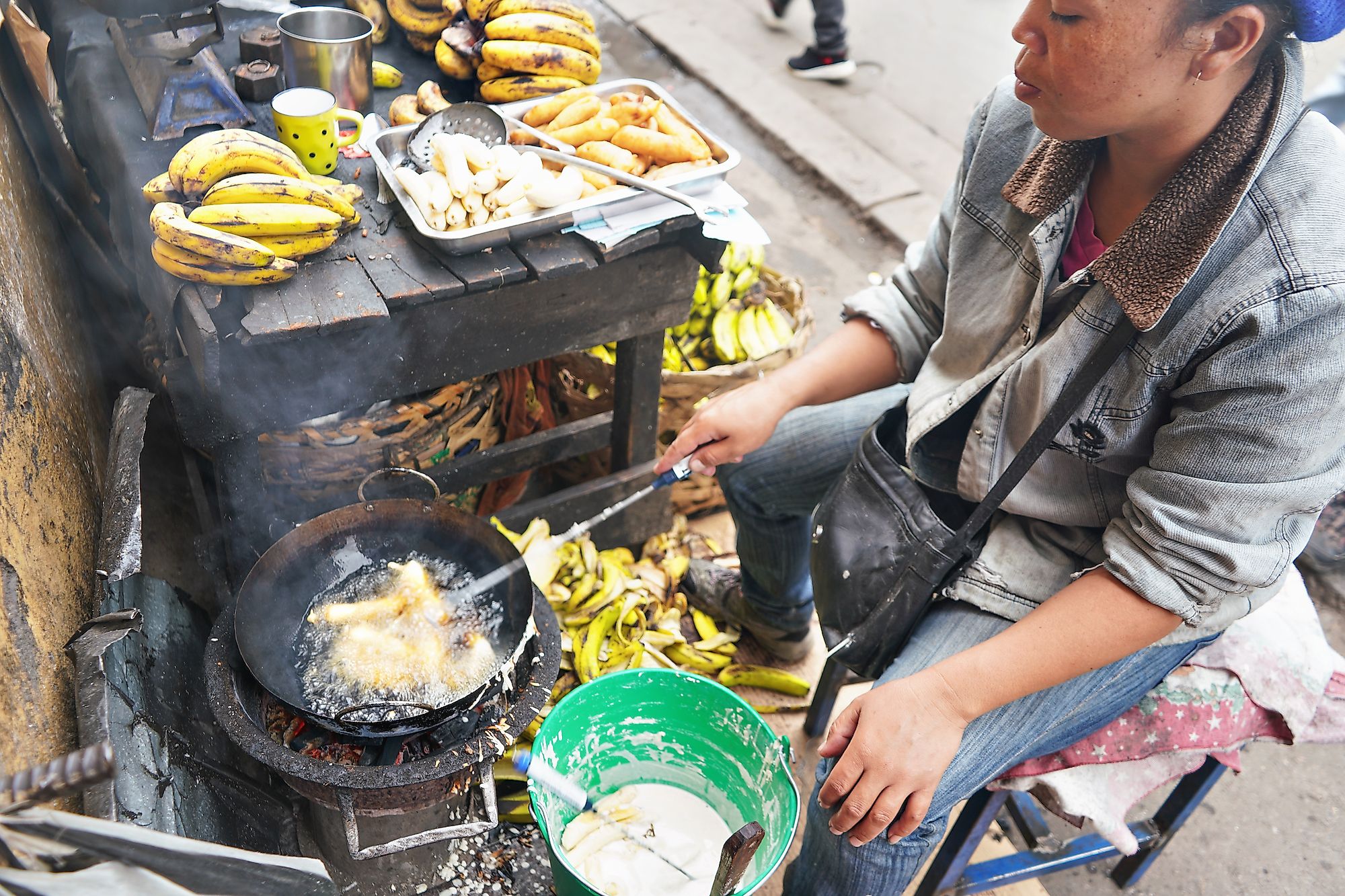 Local Malagasy woman frying bananas in oil at her stall on market next to main road. Image credit: Lubo Ivanko/Shutterstock.com