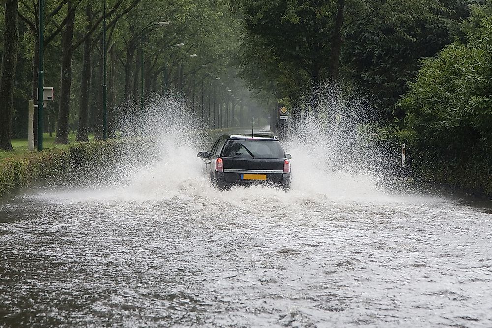 A car driving through a flooded street in the Netherlands.