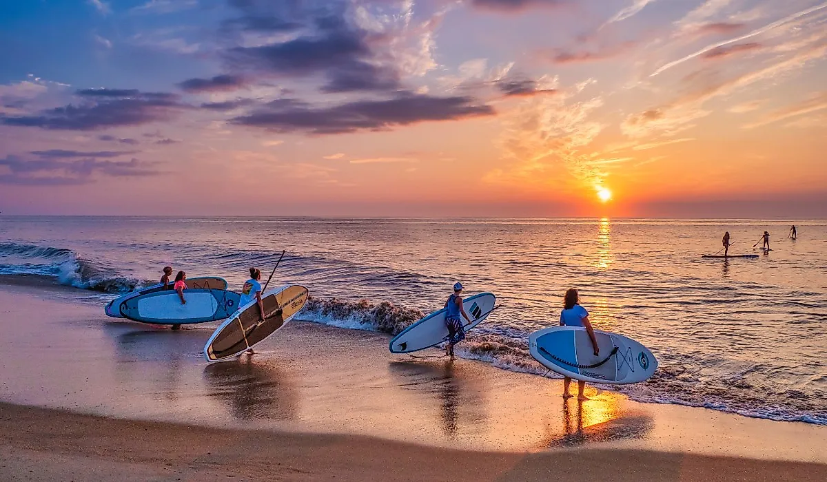 A group of young women with paddle boards on the beach in Bethany Beach, Delaware. Image credit David Kay via Shutterstock