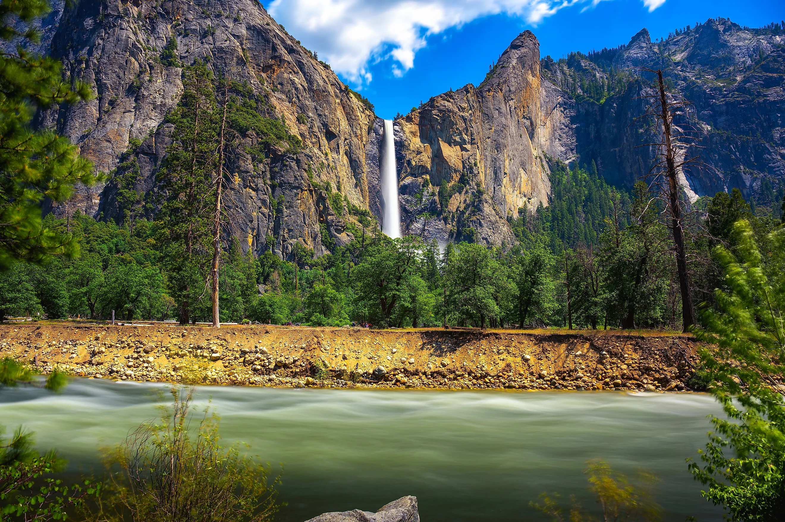 Bridalveil Fall cascading into Yosemite Valley with the Merced River in the foreground in Yosemite National Park, California. 