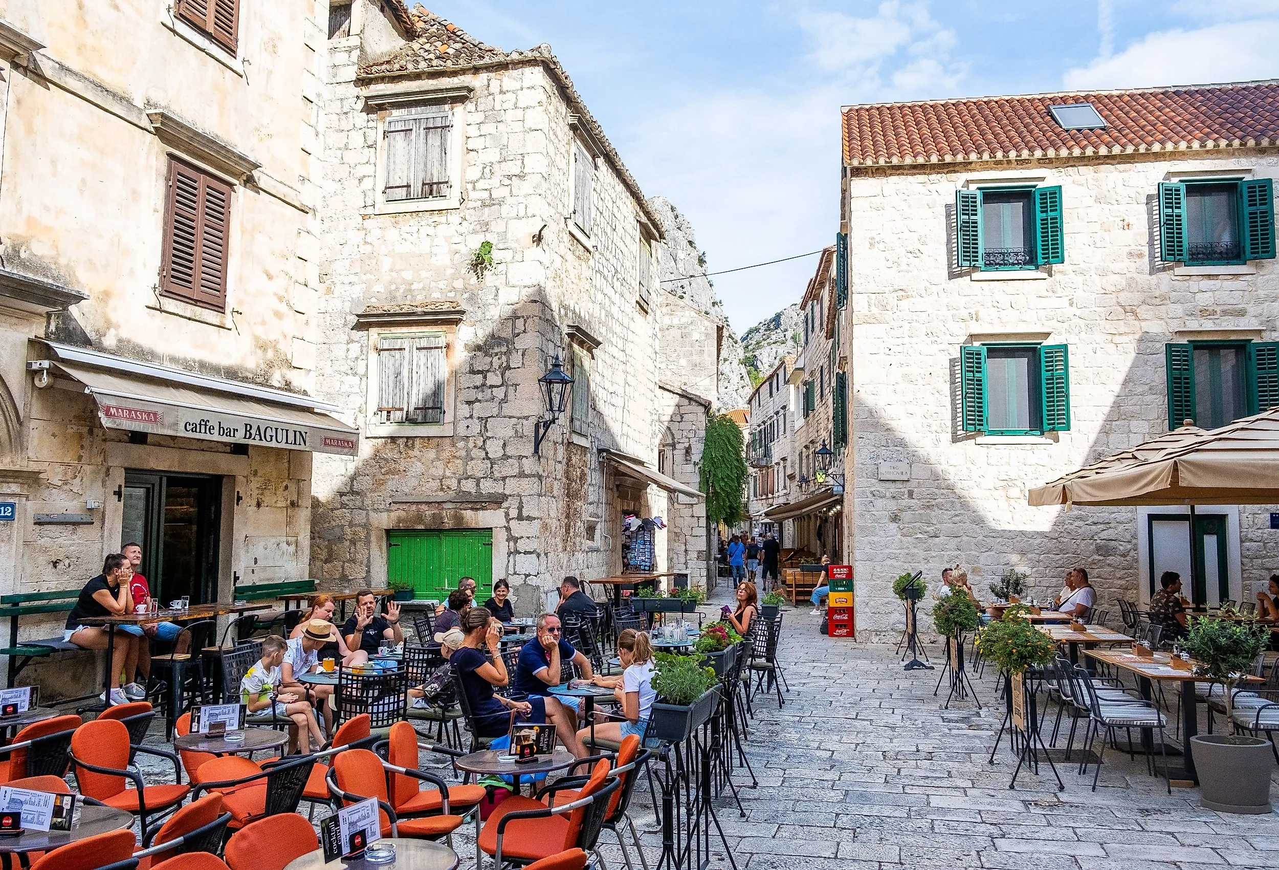 People enjoying drinks at an outdoor café in the historic center of Omiš. Image credit: Ivan Klindic via Shutterstock.