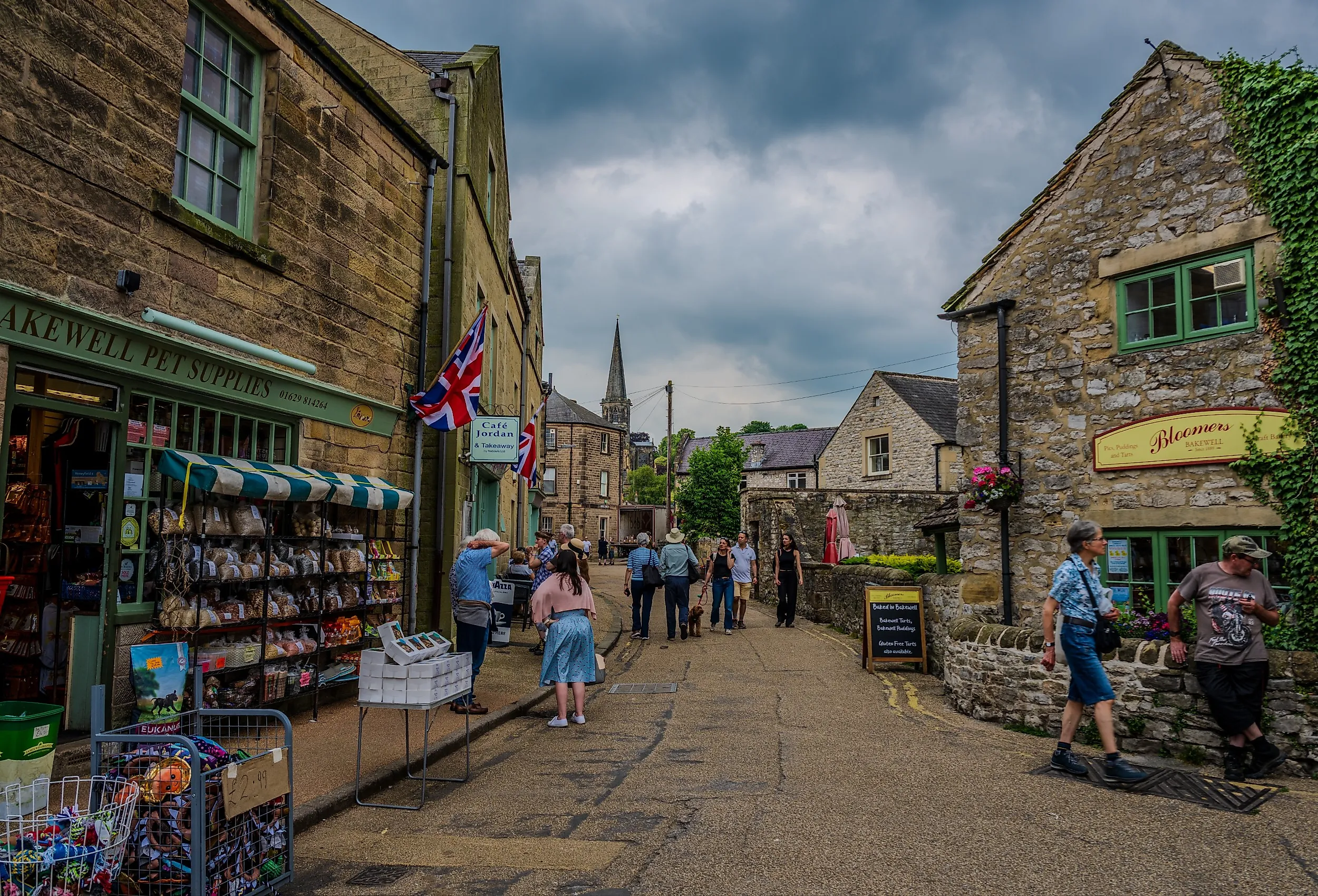 Stone shopfronts and pedestrians line a narrow street in Bakewell, Derbyshire. Editorial credit: Emad Aljumah / Shutterstock.com