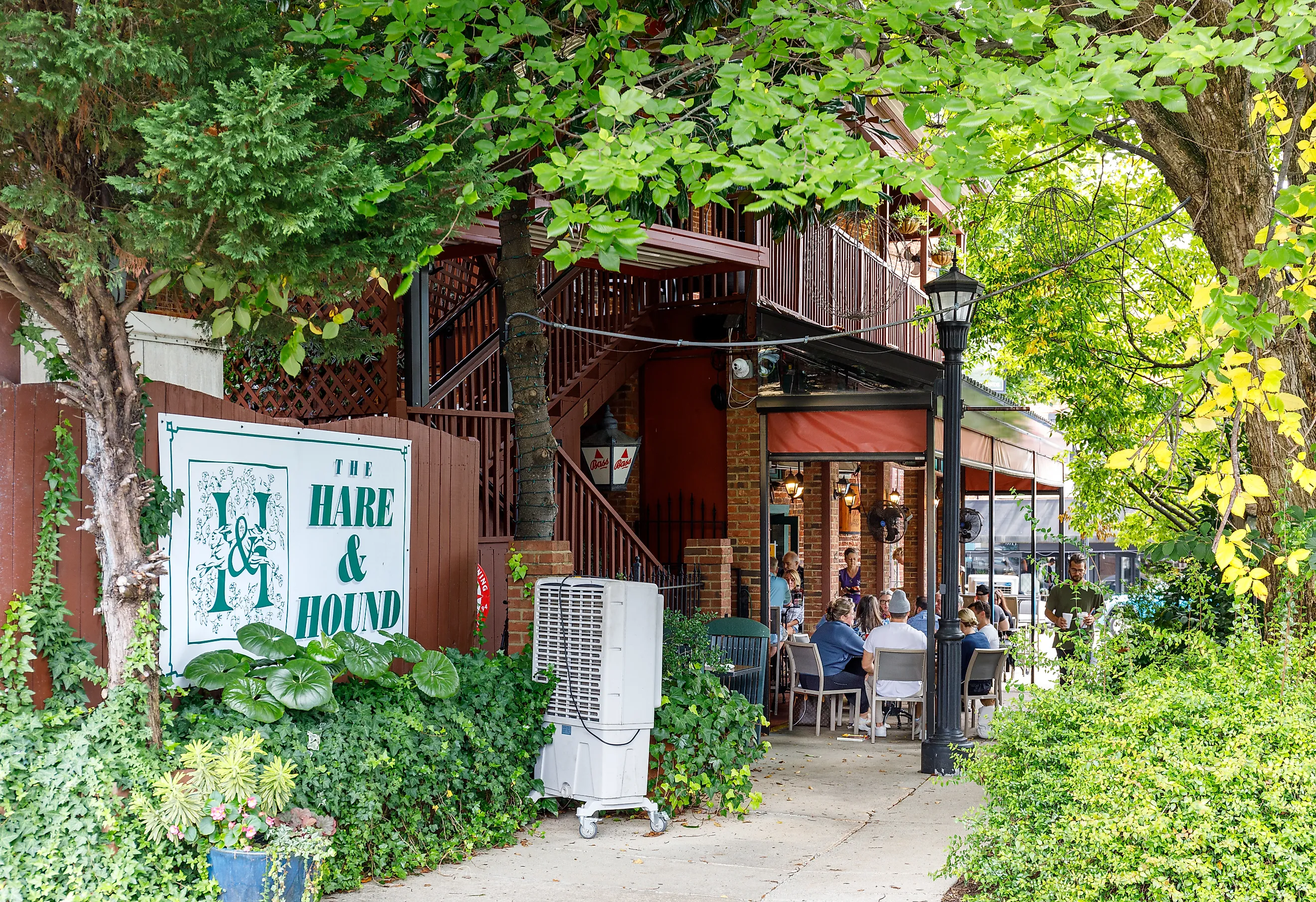 Landrum, South Carolina, USA-7 September 2025: Side view of The Hare and Hound restaurant, showing sign, covered outside dining with customers at tables, greenery. via J. Michael Jones on iStock.com