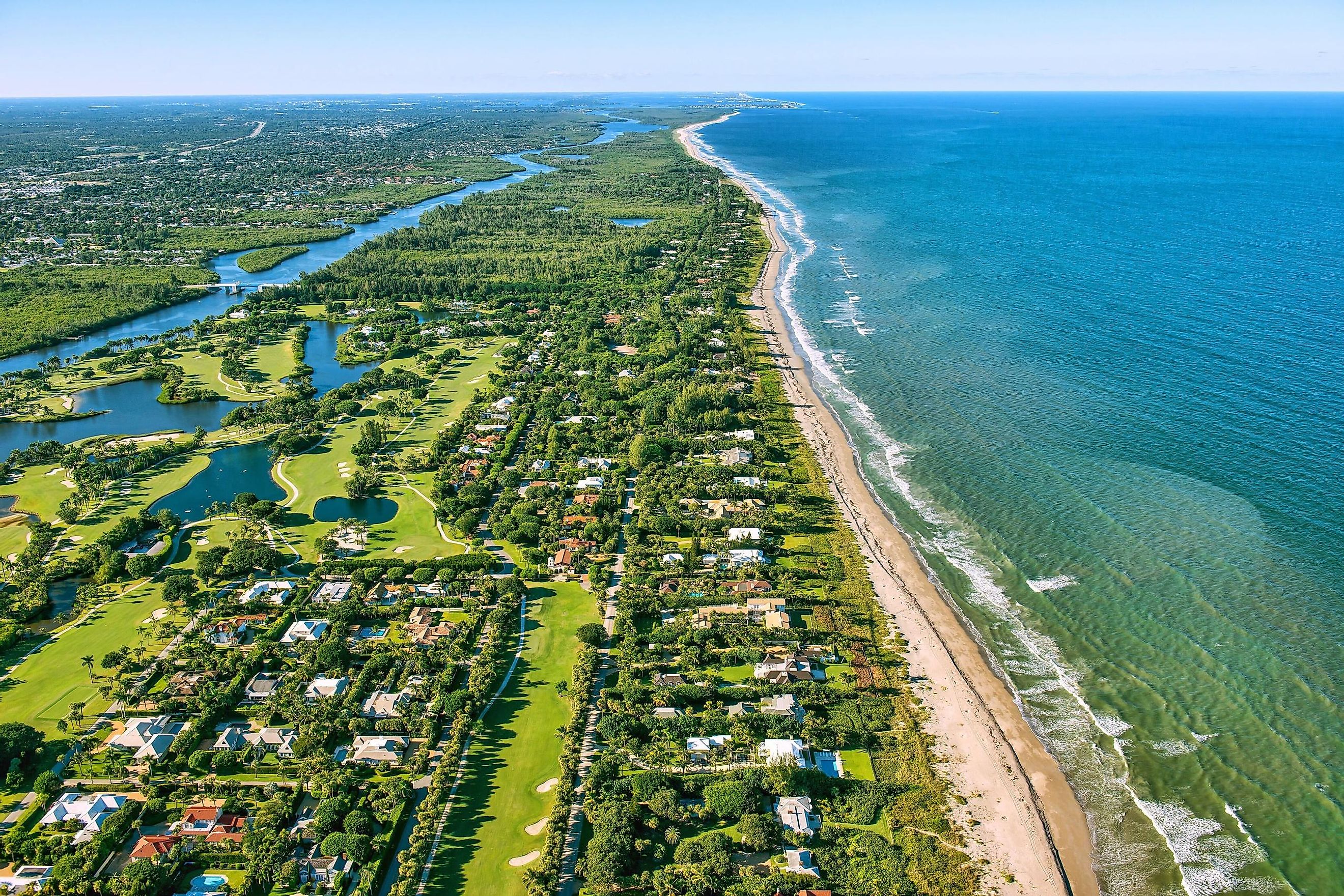 aerial view looking north, of Jupiter and Hobe Sound, Florida, along the Atlantic Ocean coast, lined by the beach and dotted by luxury homes golf courses