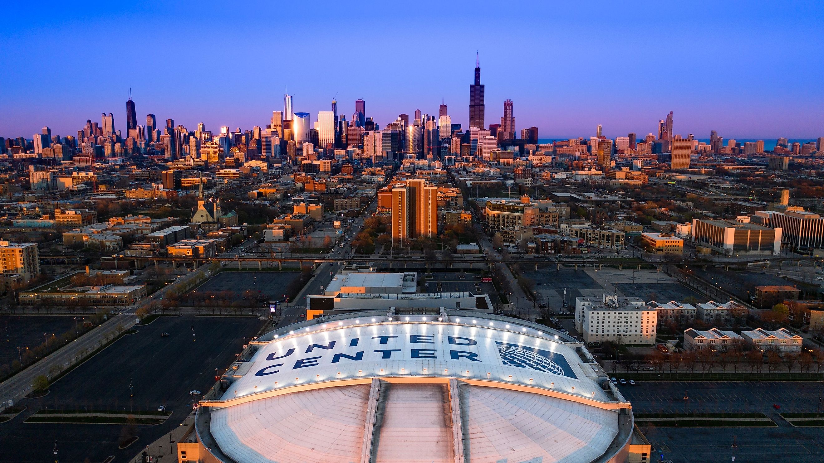 Beautiful Aerial View of Iconic United Center Stadium with Chicago Skyline in Background at Blue Hour. 