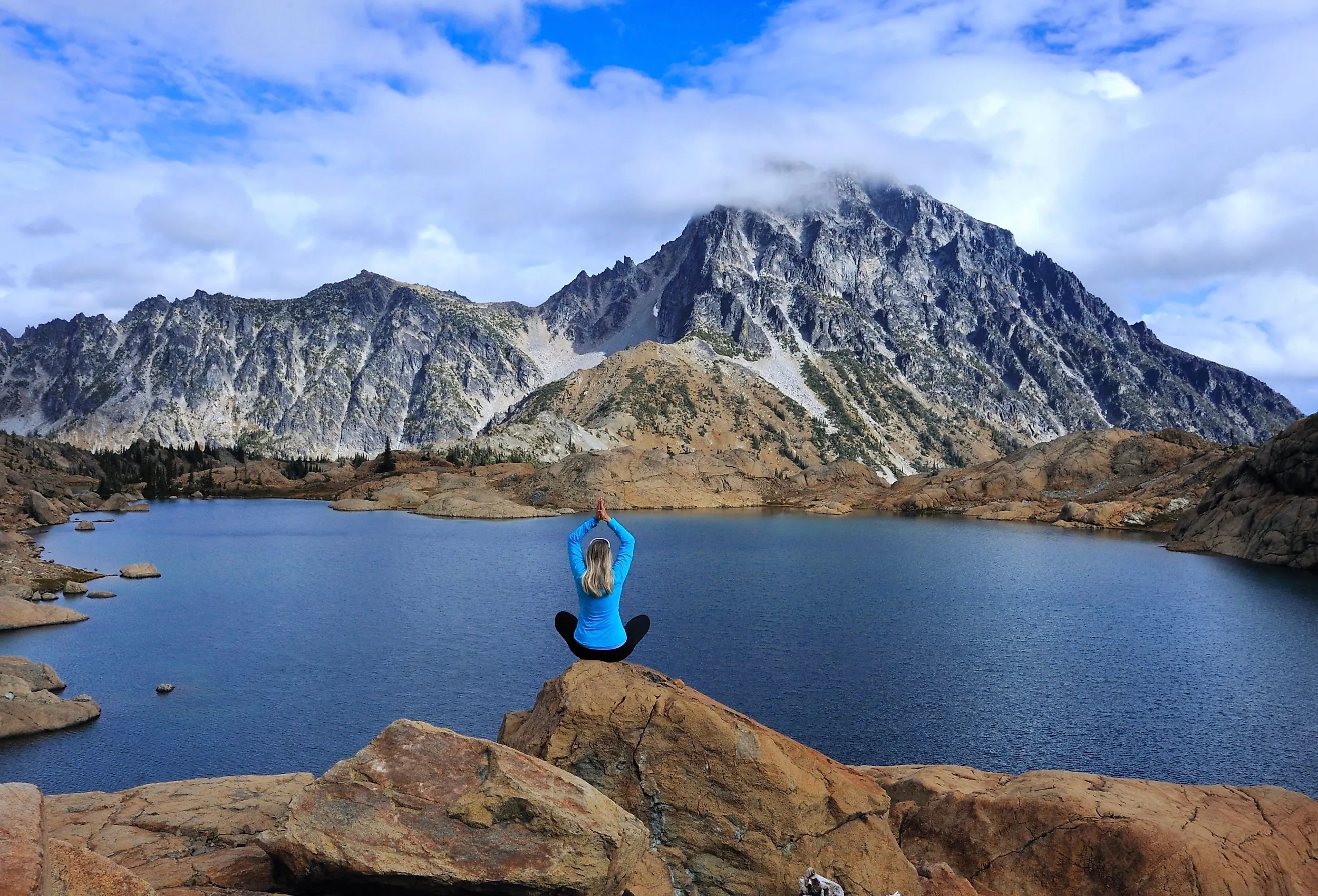 Woman doing a yoga post on a rock overlooking Ingalls Lake, WA.