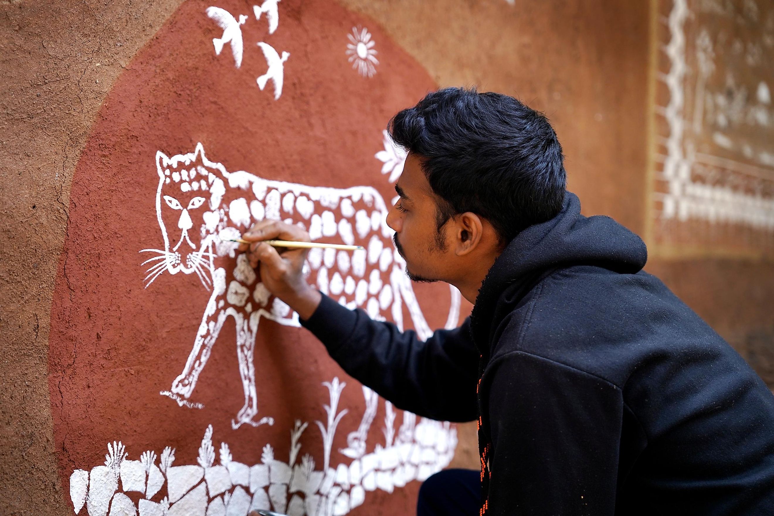 A Warli artist painting the Waghoba on the wall of a home in Mumbai's Aarey Milk Colony.