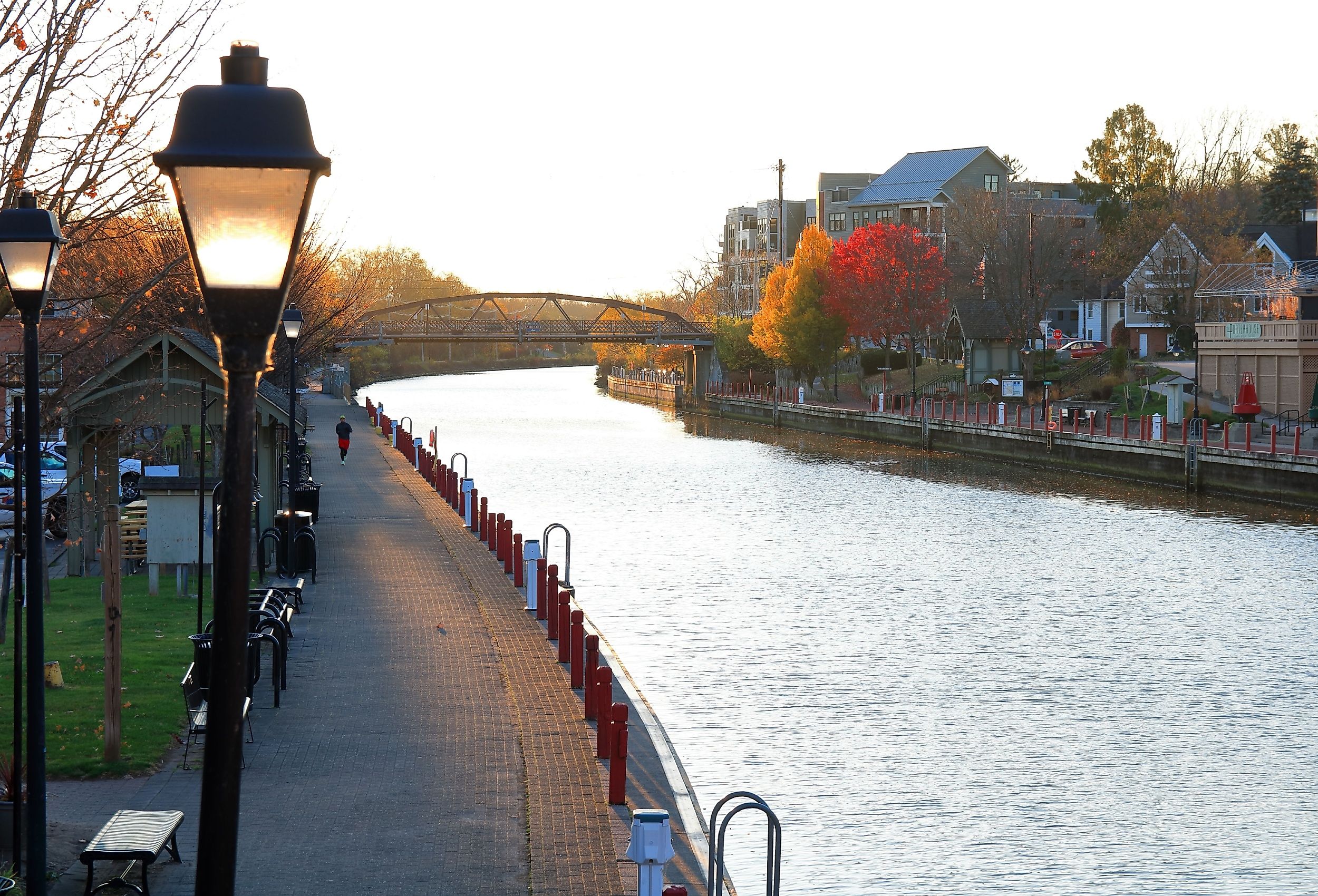 A jogger running along the Erie Canal Path in Fairport, at sunrise on a clear, blue sky morning. Fall colors are displayed on surrounding trees. Image credit Hike Kayak Fish via Shutterstock.com