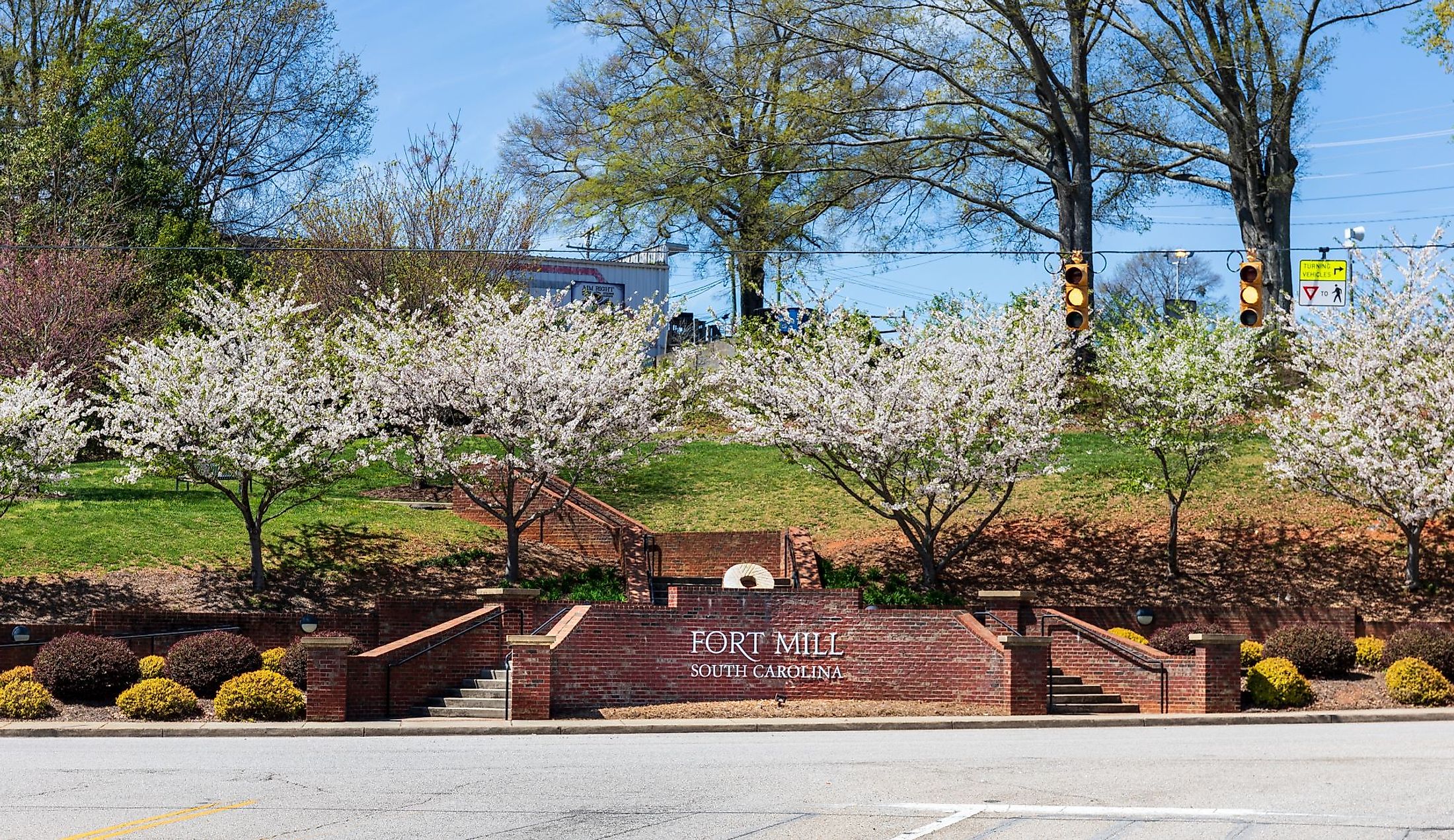 "Fort Mill" sign on a brick wall with blooming dogwoods at entrance to Main Street in Fort Mill, South Carolina. Editorial credit: Nolichuckyjake / Shutterstock.com