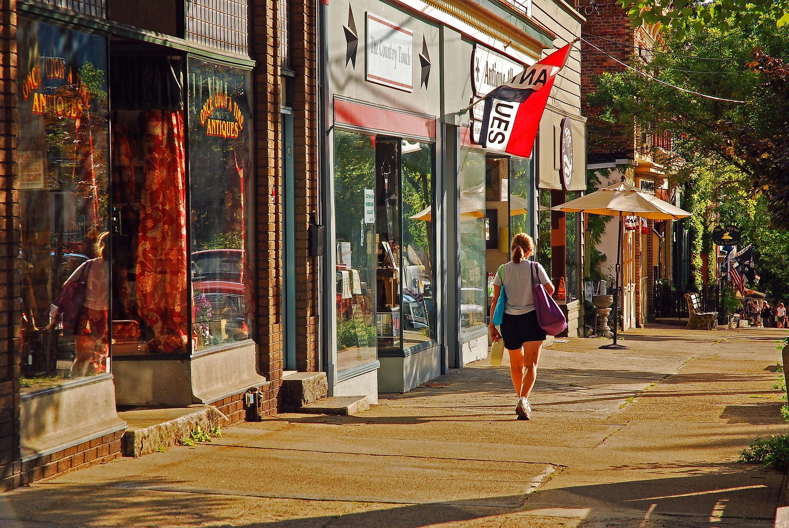A young woman walks past independent stores and boutiques on a sunny day in Cold Spring, New York