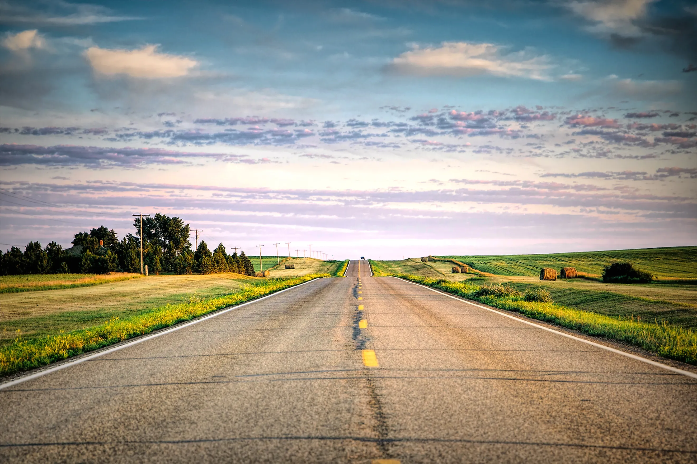 a long country highway rural highway road in North Dakota at sunset with a colorful sky. Editorial credit: adobe stock