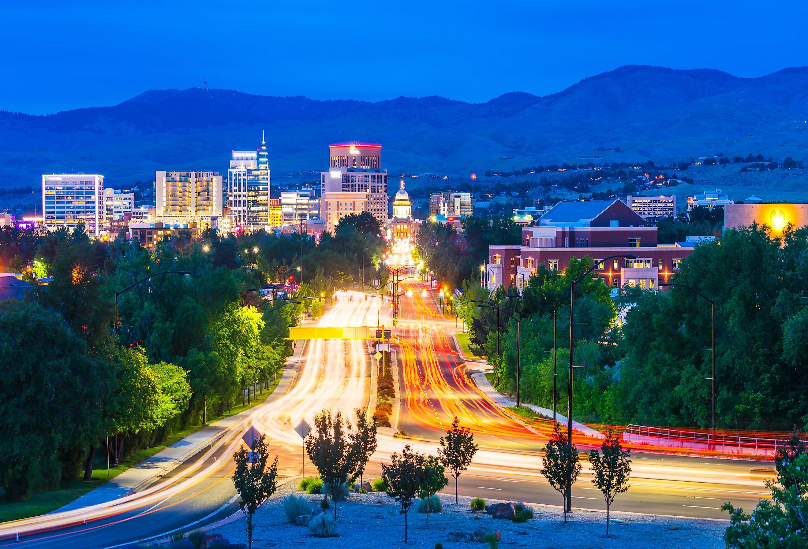 Boise, Idaho cityscape at night with traffic lights and Rocky Mountains in the background. Image credit Checubus via Shutterstock.