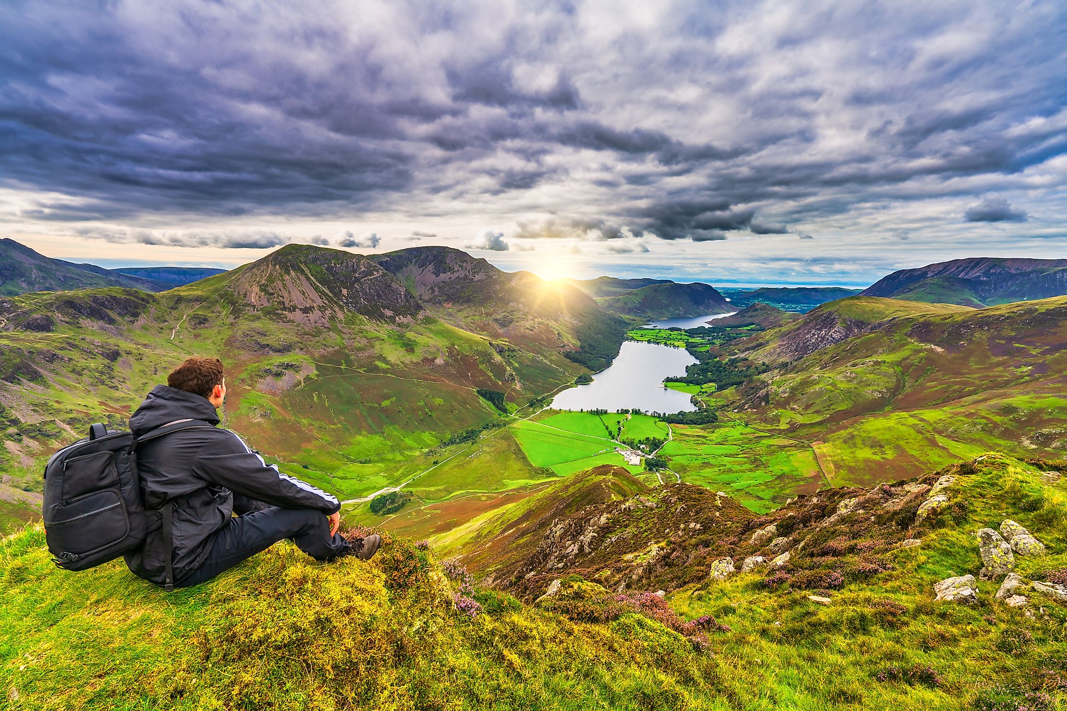 A hiker enjoying the spectacular sunset overlooking the Buttermere lake in Lake District. Cumbria. UK.