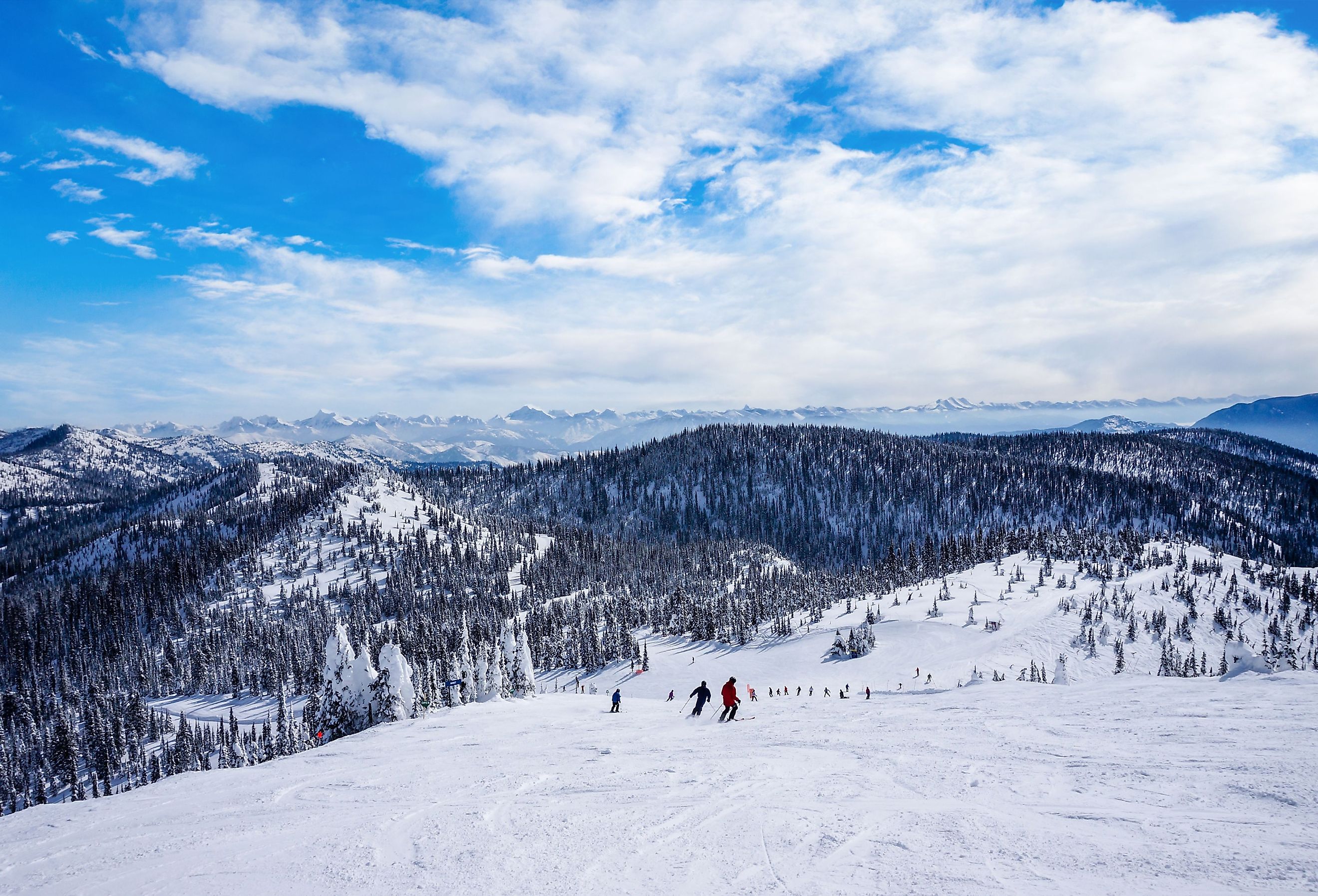 Unidentifiable skiers going down from the summit at Big Mountain in Whitefish, Montana, west of Glacier National Park, USA.