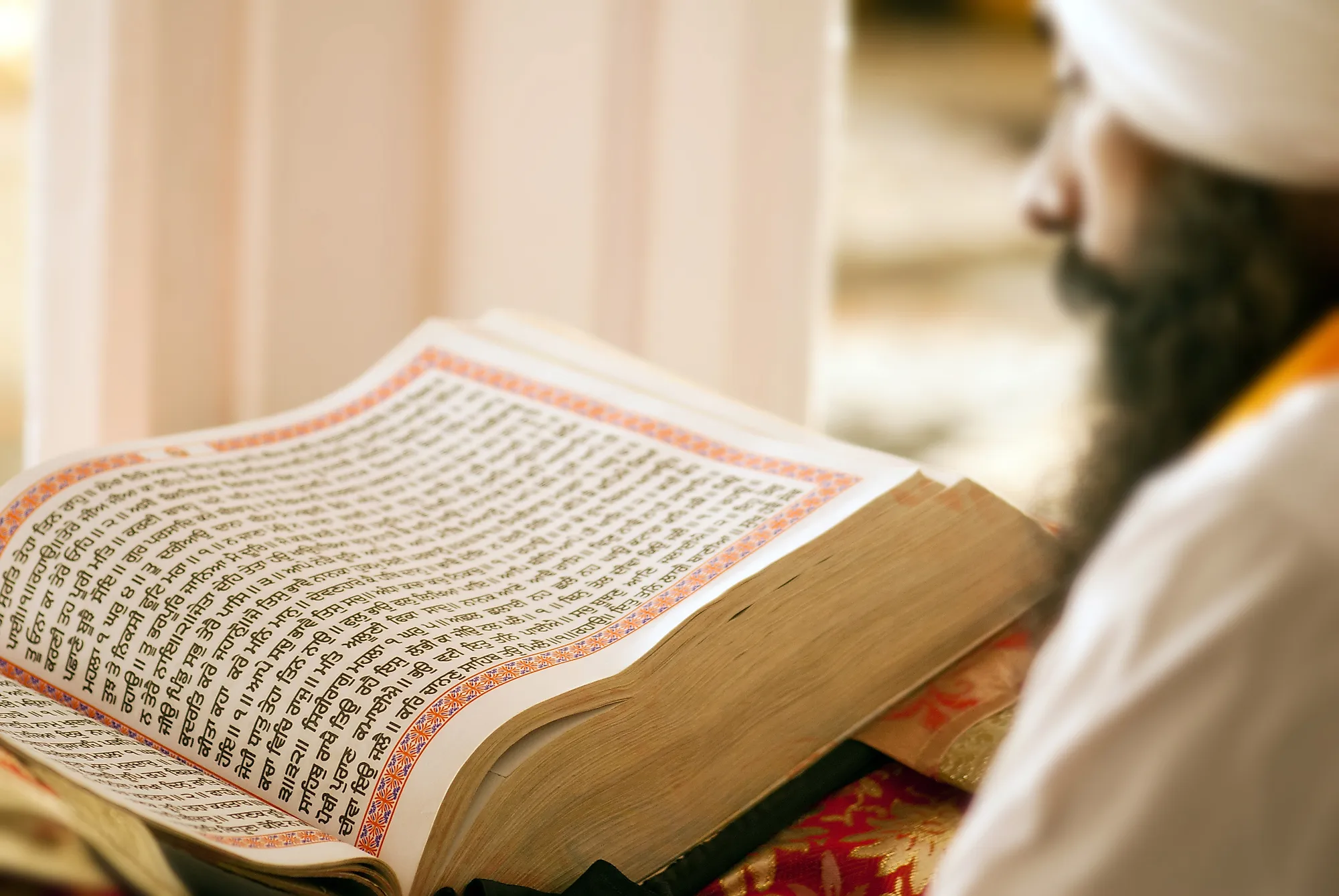 A holy man reading a copy of the Guru Granth Sahib written in Gurmukhi script in Hazur Sahib Gurudwara, Maharashtra, India.. Editorial credit: Tukaram.Karve / Shutterstock.com