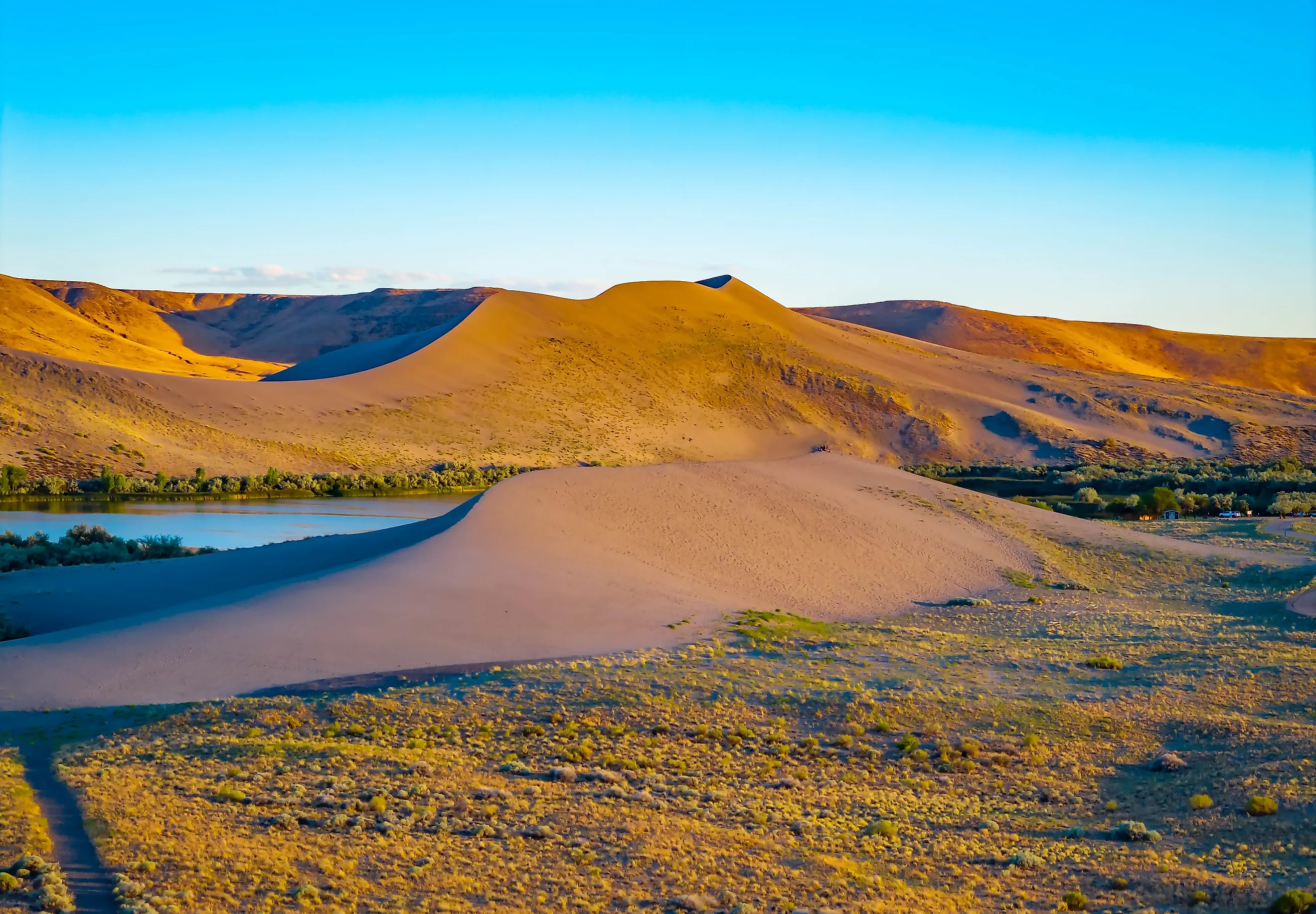 Vibrant golden sunset glow illuminates the towering sand dunes at Bruneau Dunes State Park. Credit: Photo Spirit/ Shutterstock.com