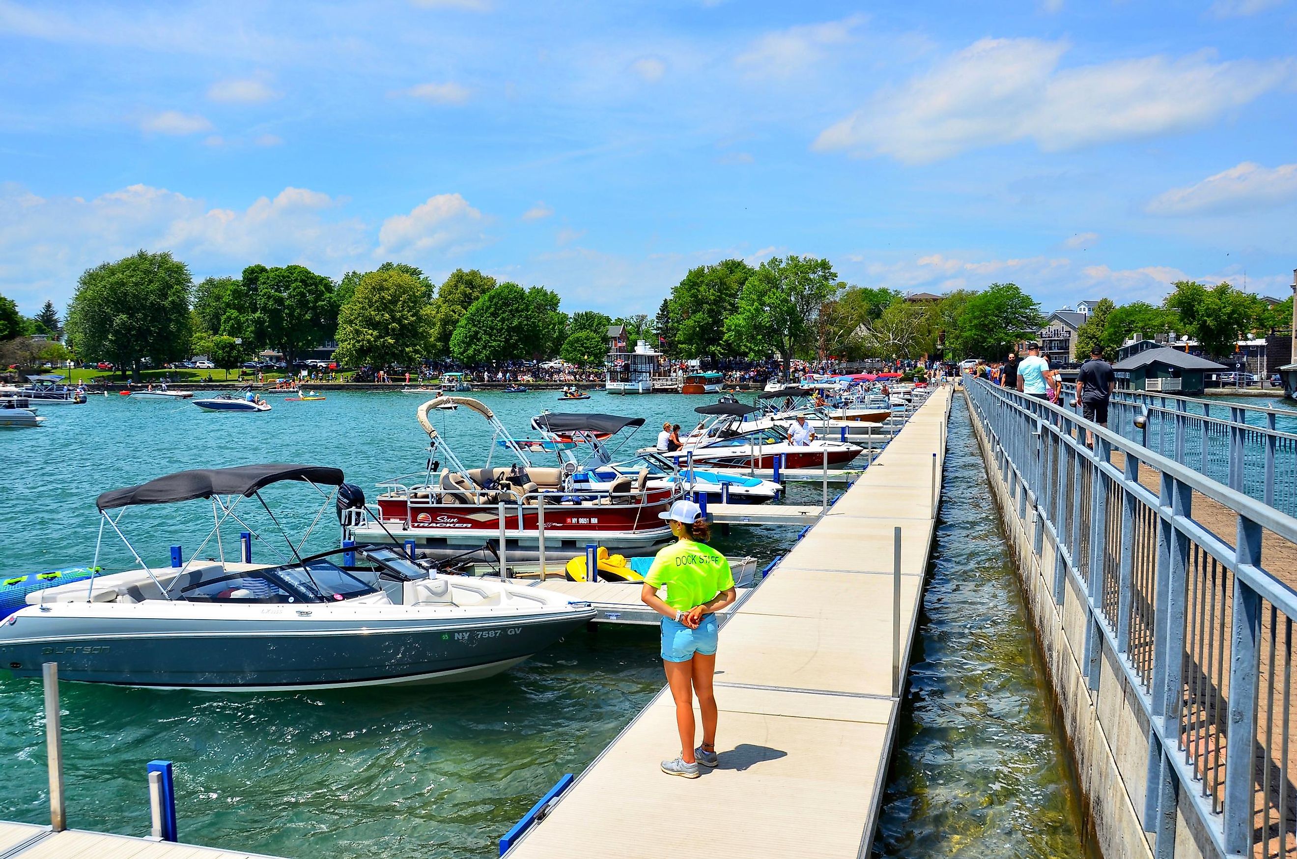 SKANEATELES, NEW YORK - June 27, 2021: Pier and luxury boats docked in the Skaneateles Lake, one of the Finger Lakes. A crowded day due to high school graduation celebration event. Dock staff on site.