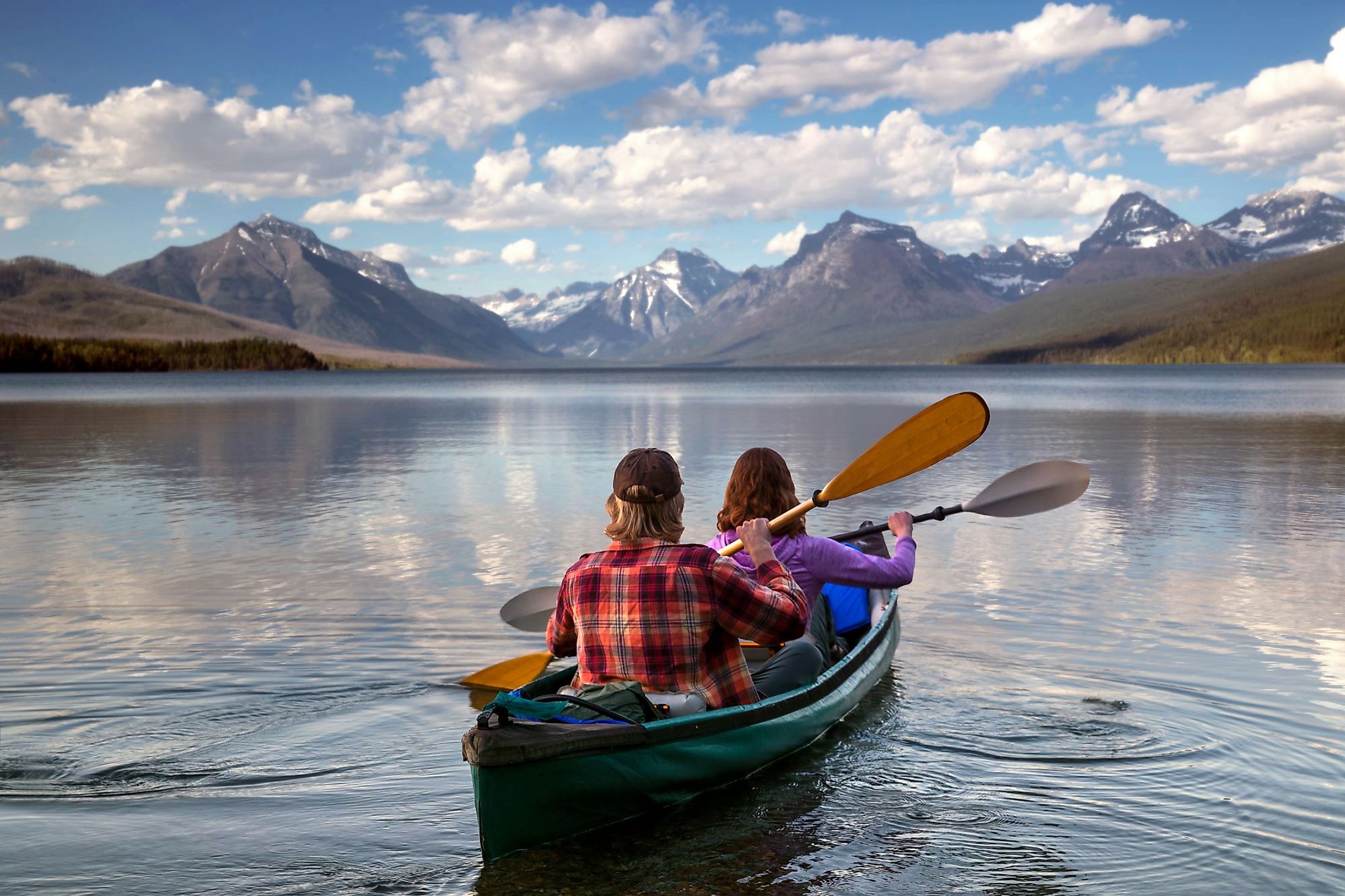 Adventurous traveling couple rowing a boat on a perfect scenic lake in Montana. 