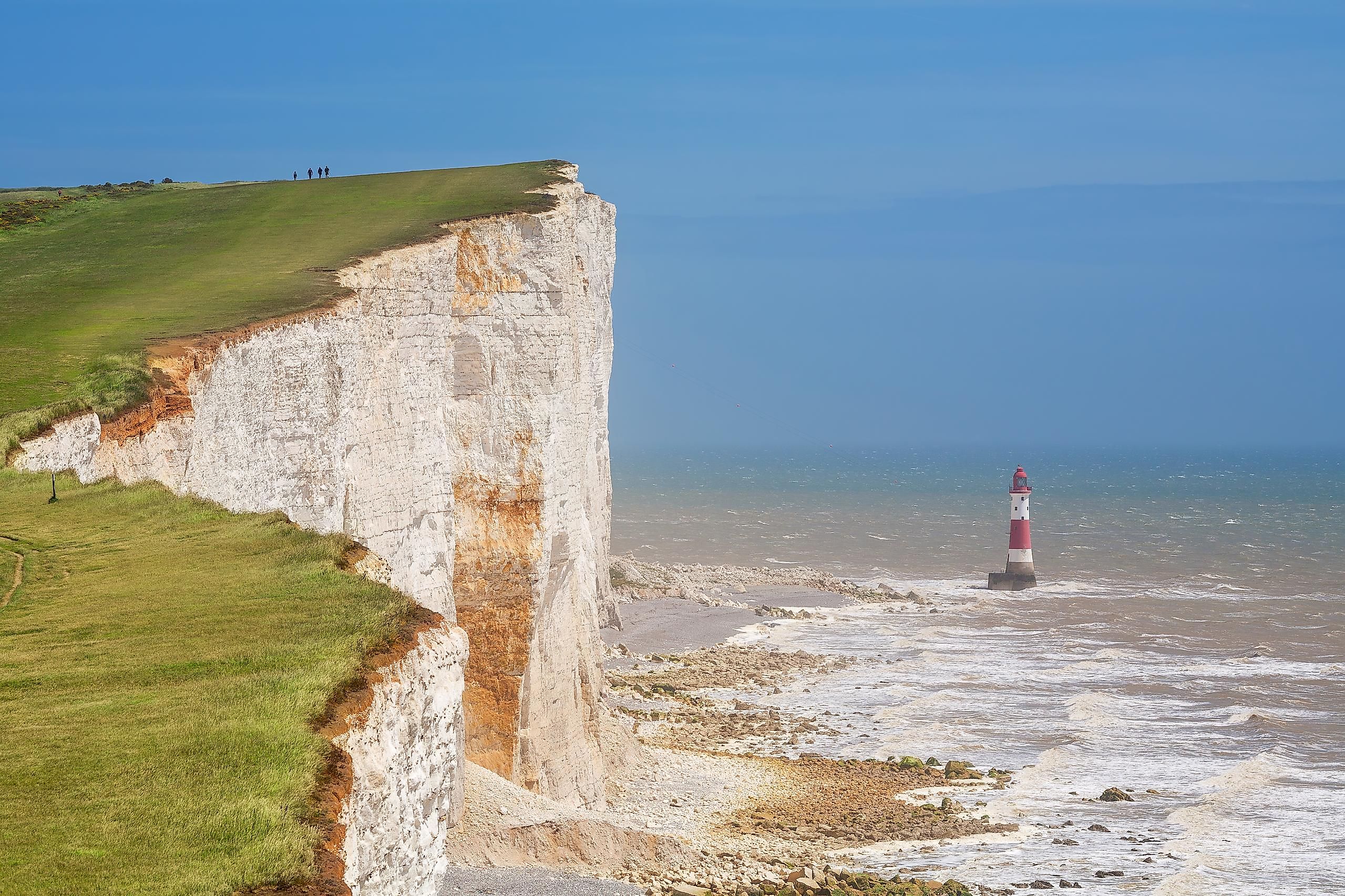 The world famous chalk cliffs at Beachy Head, with an offshore lighthouse below their base.
