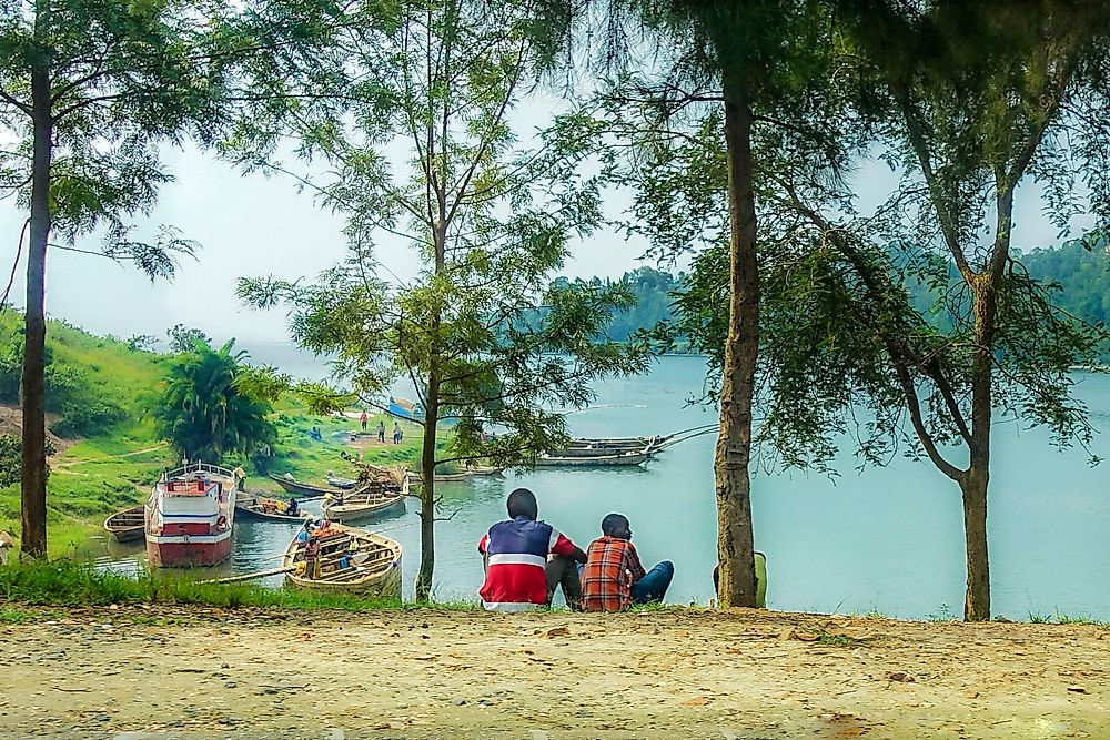 Rwandan men sit by a lake.