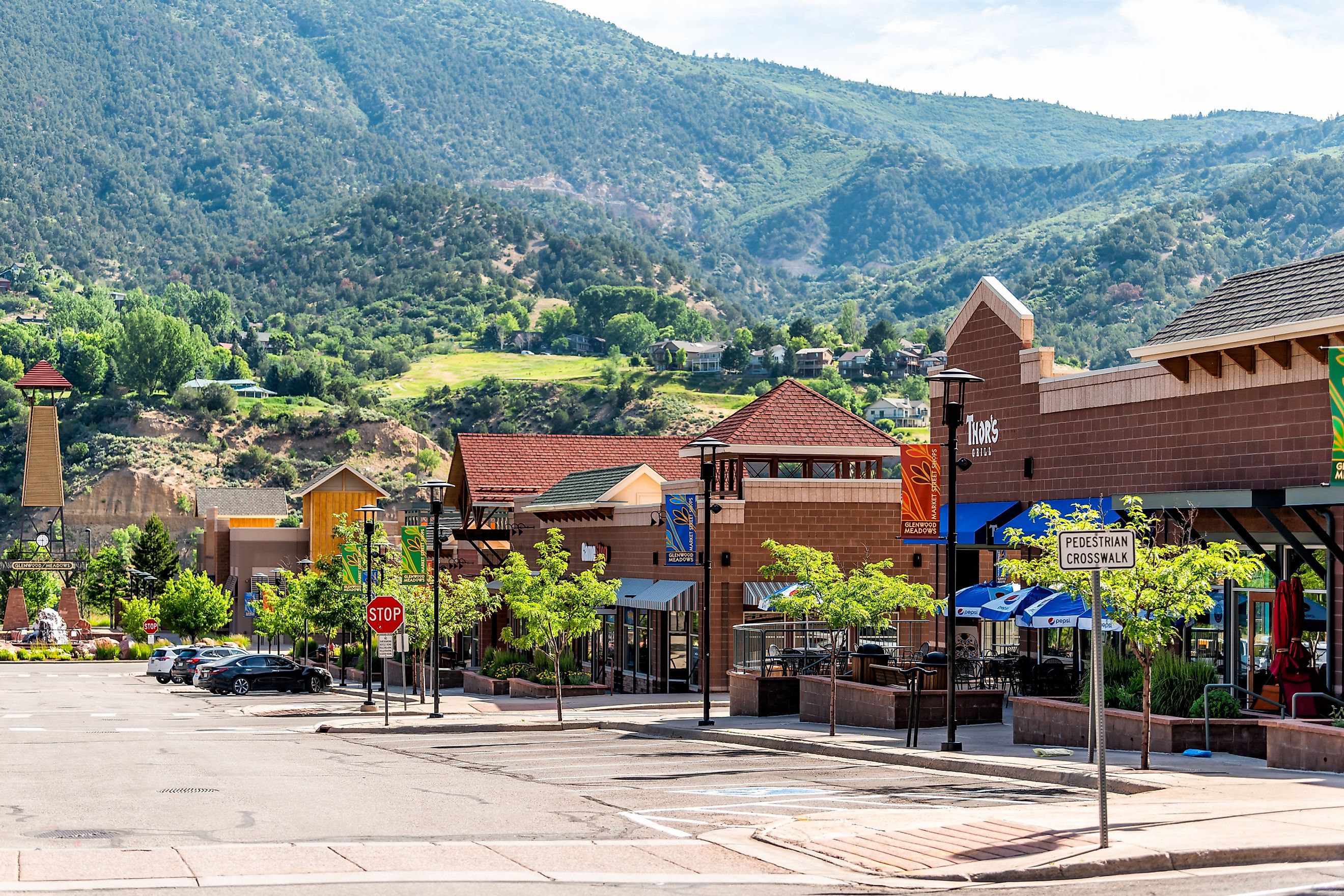 Shopping meadows mall park buildings stores in Colorado town near red mountain and cars parked