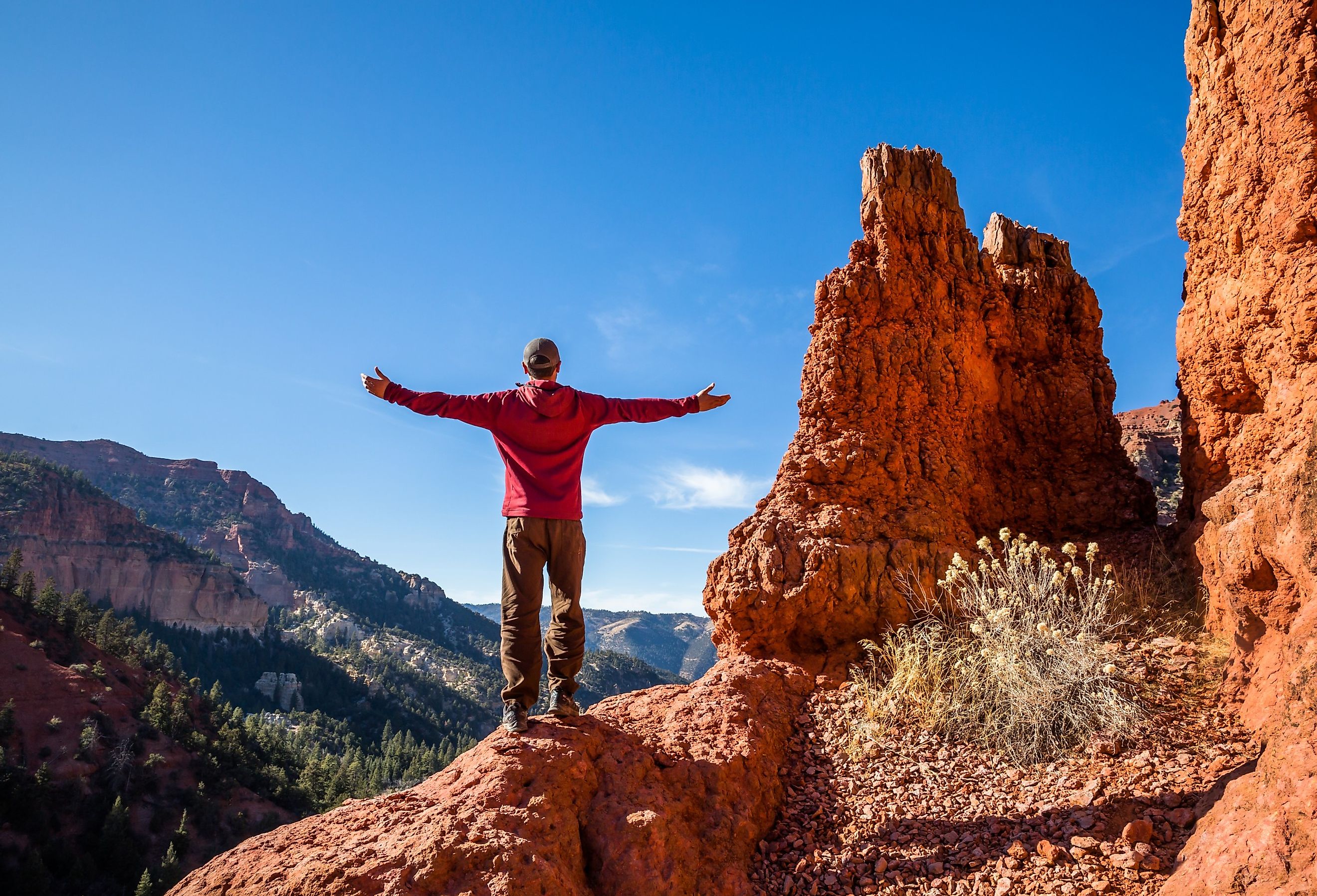 Hiker standing atop red rock formation in the Southern Utah desert near Cedar City.