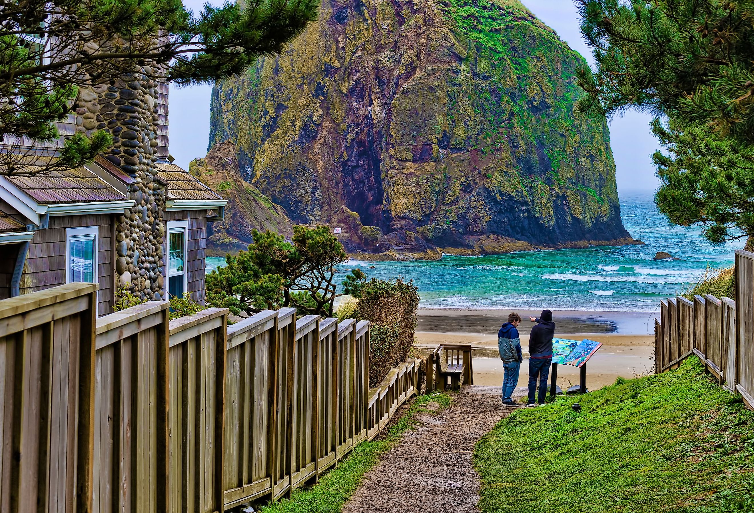 Two brothers at the end of a public beach access path at Cannon Beach, Oregon, with the stunning coastline and Haystack Rock.