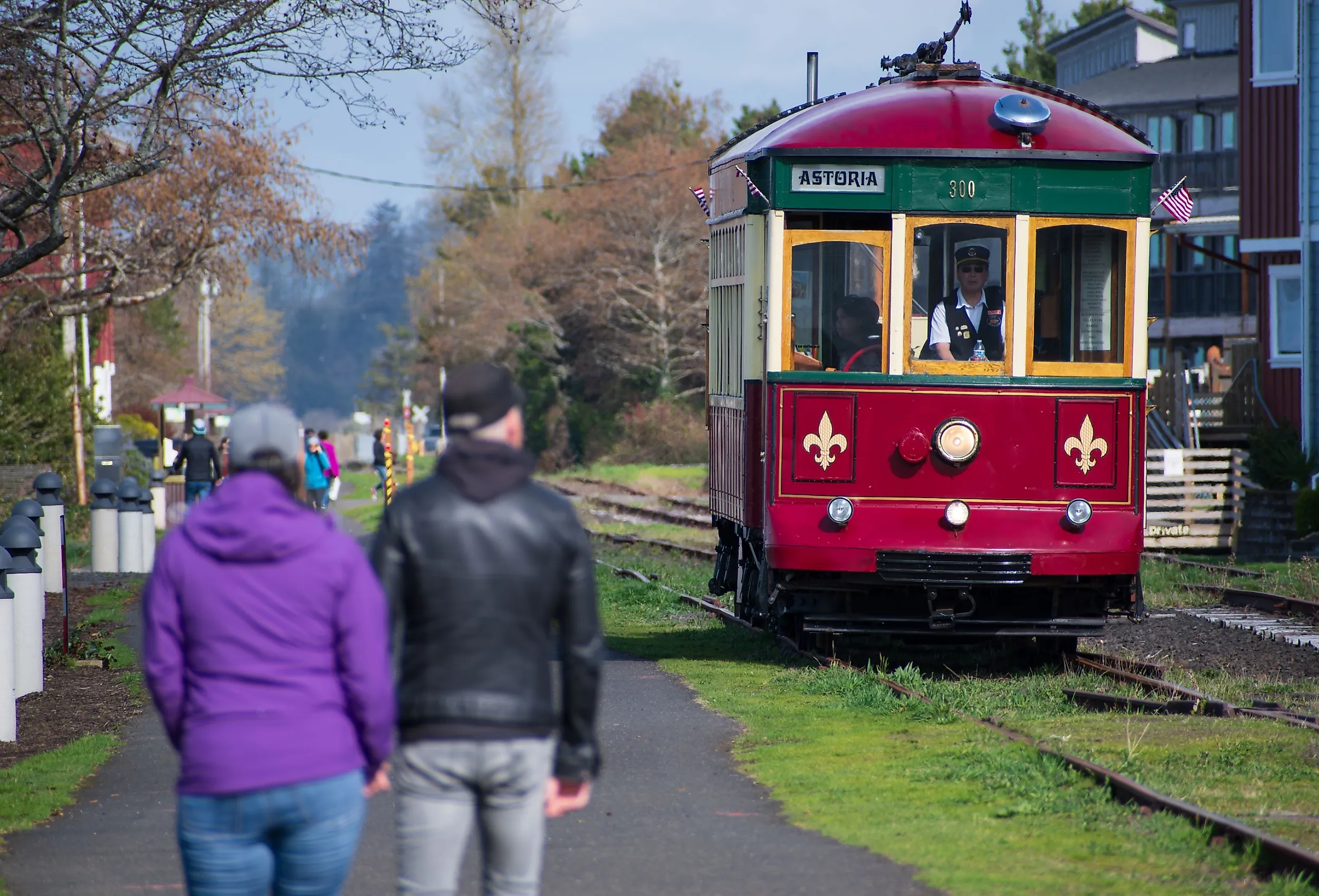 A couple walks along the Astoria Riverwalk as the Astoria Riverfront Trolley passes by. Image credit: Charles-McClintock Wilson via Shutterstock.