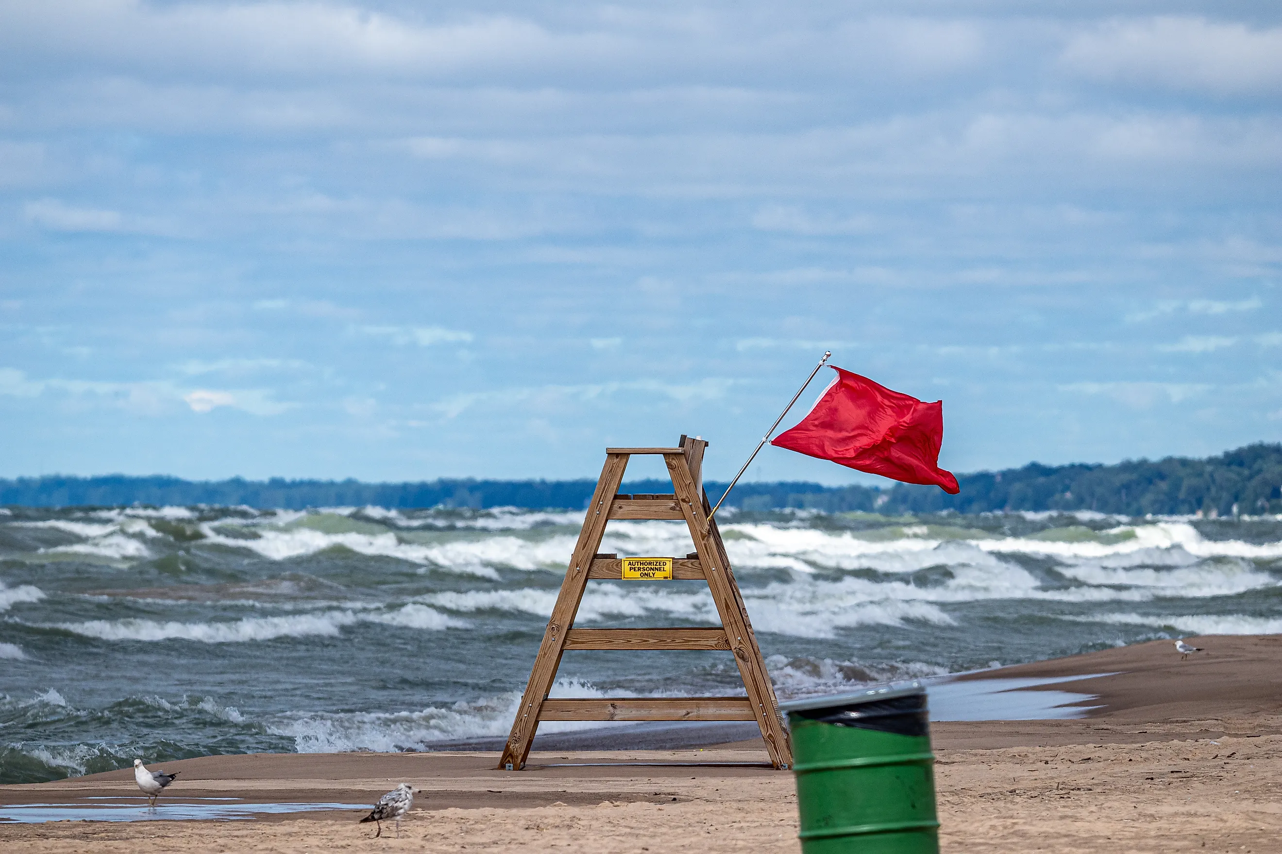 Red warning flag flying on a wooden lifeguard chair at Lake Michigan during hazardous water conditions