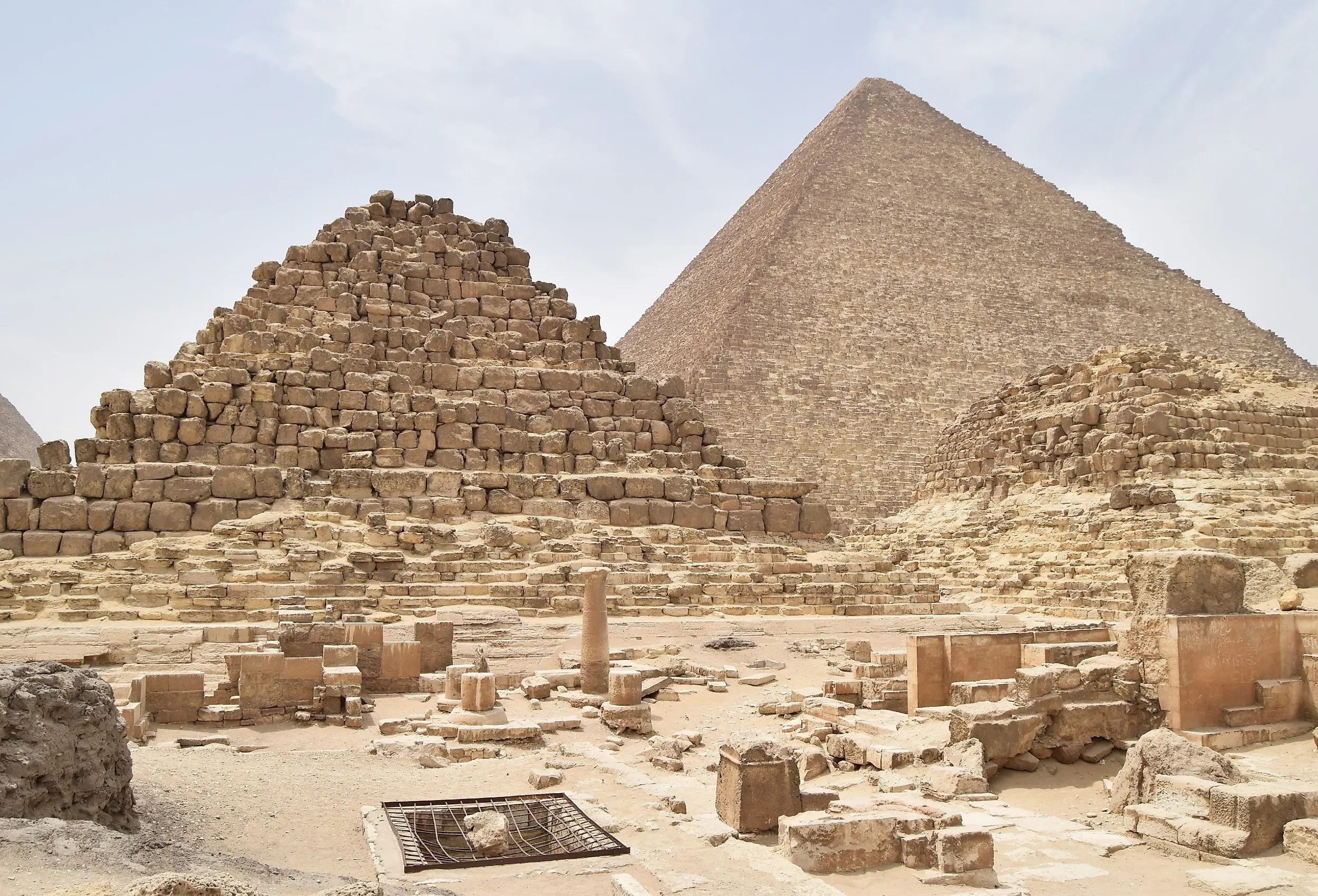 Pyramids of Giza complex in Cairo, Egypt, with Menkaure, Khafre, and Khufu pyramids under clear desert sky.