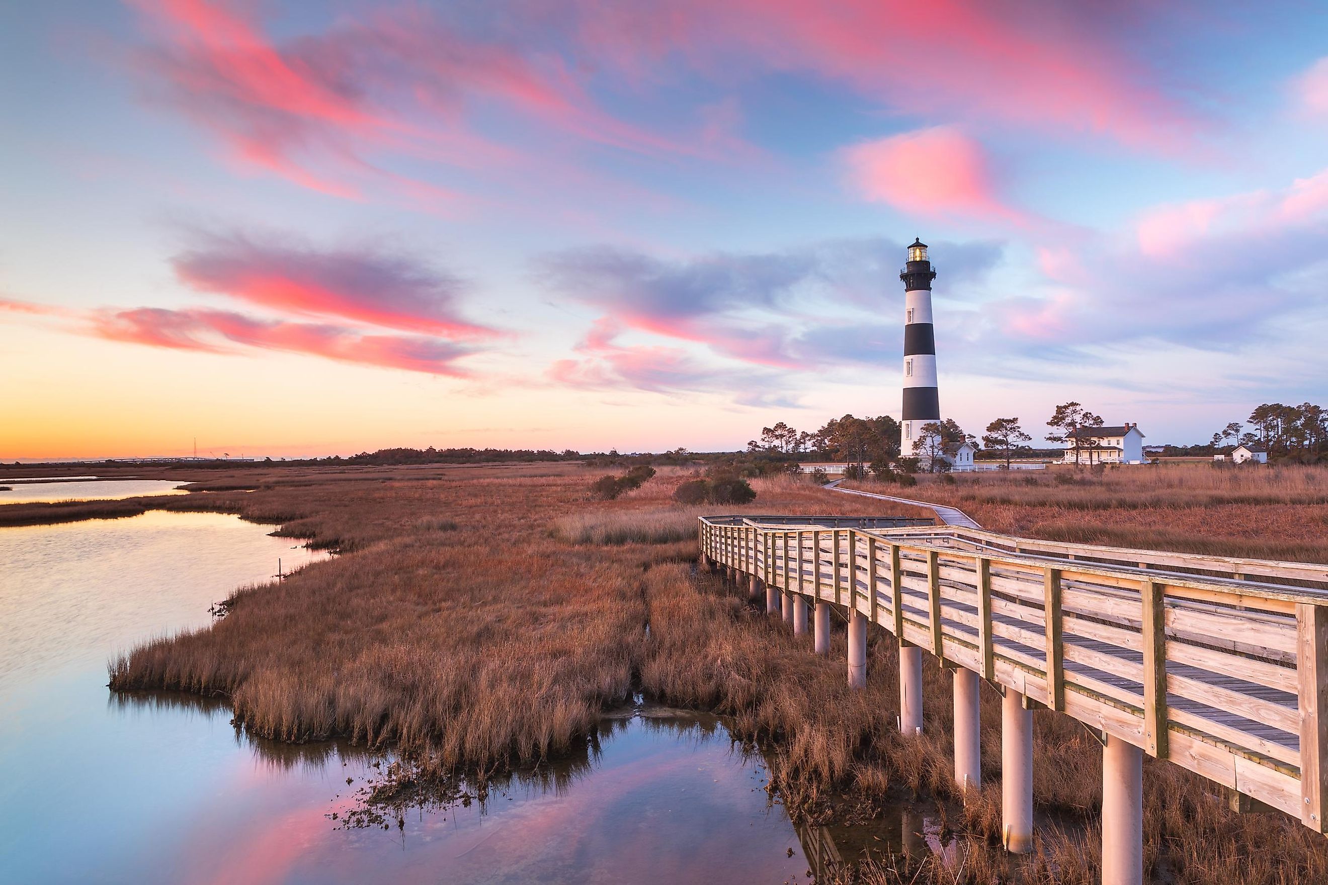 Clouds stream like pink ribbons in the sky over the marsh and lighthouse on Bodie Island on the Outer Banks of North Carolina.