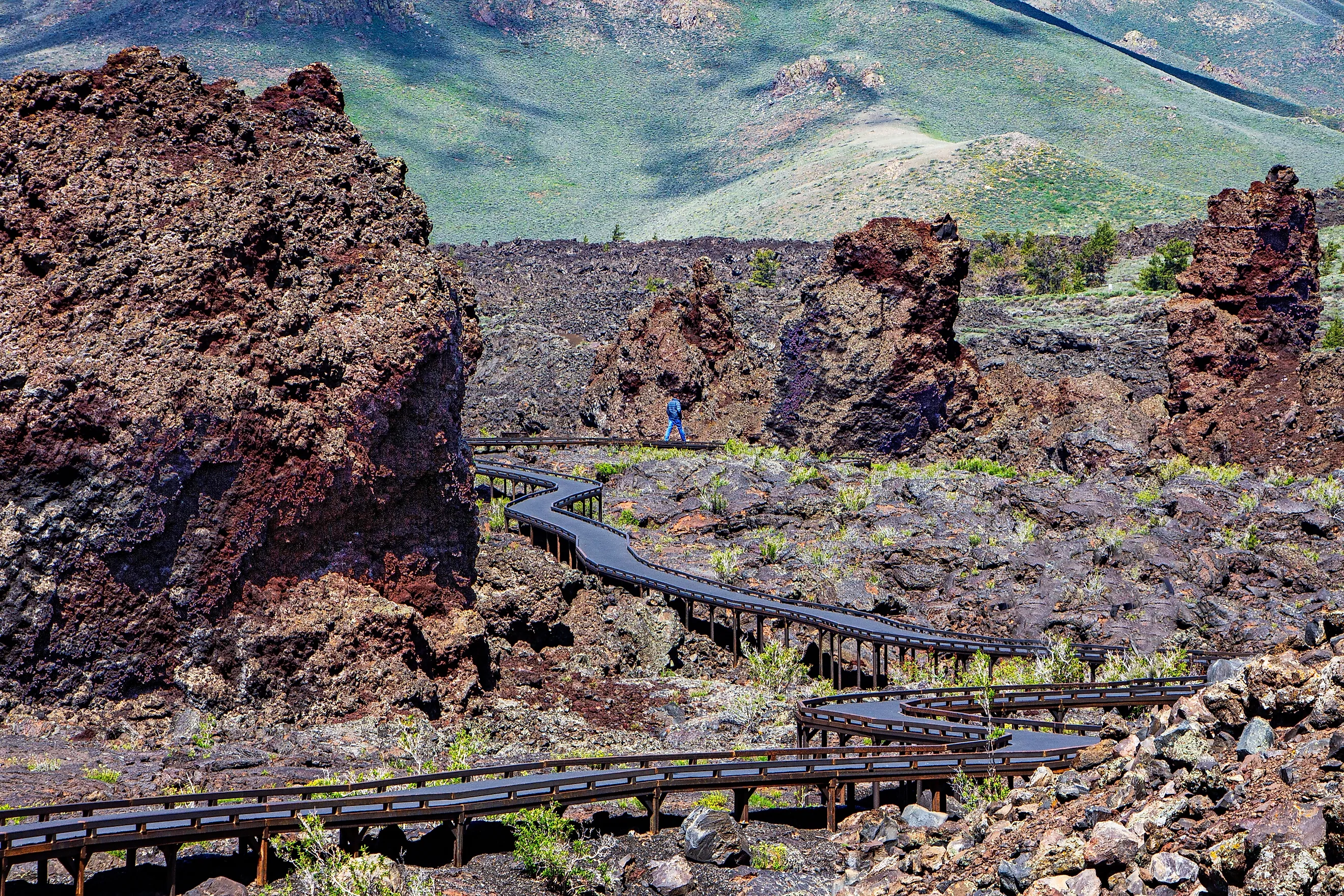 A visitor walks along the snaking boardwalk along the North Crater Flow Trail, Craters of the Moon National Monument, ID