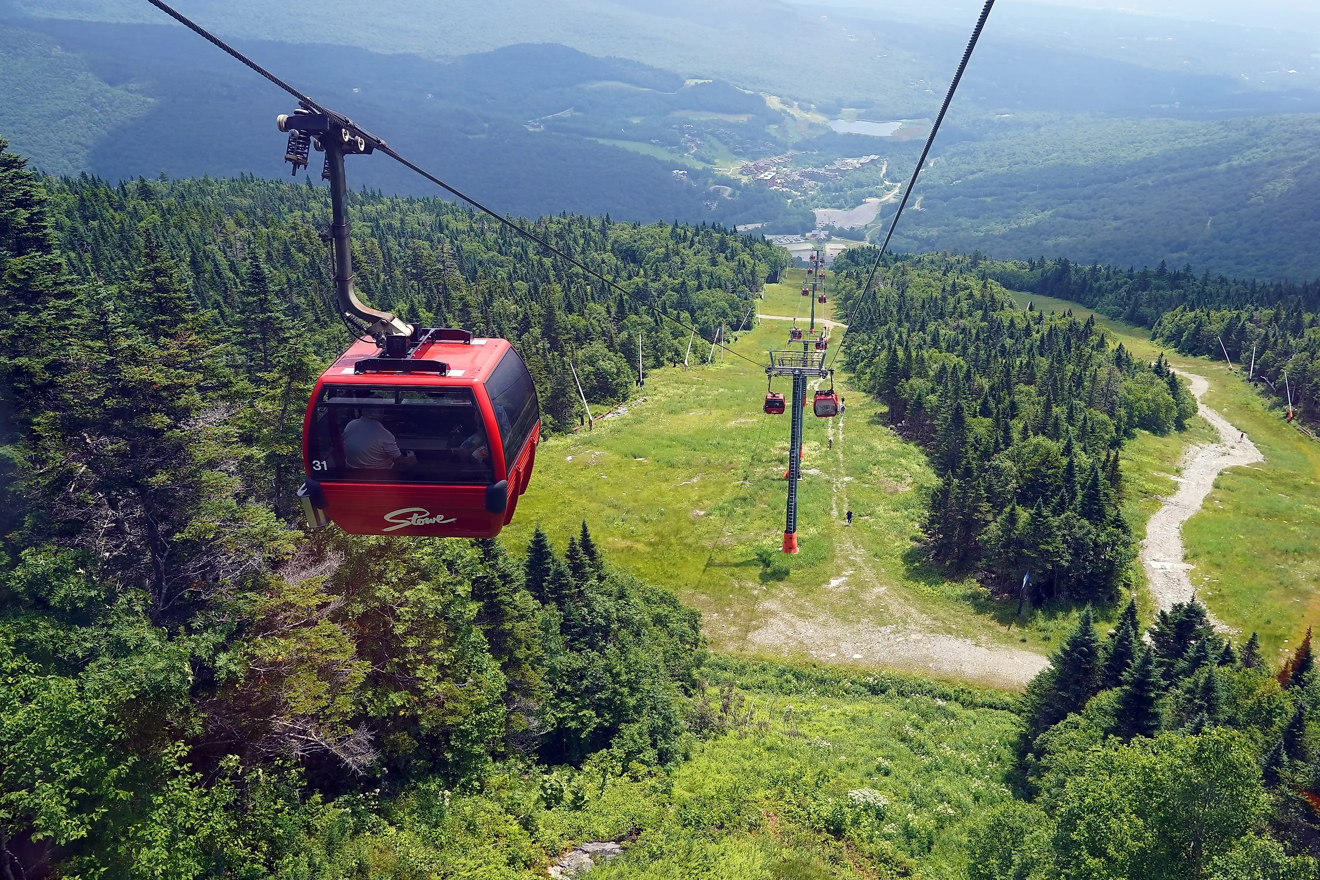 Red skiing gondolas travel up a mountain in the ski town of Stowe, Vermont. Image credit: Adam McCullough / Shutterstock.com