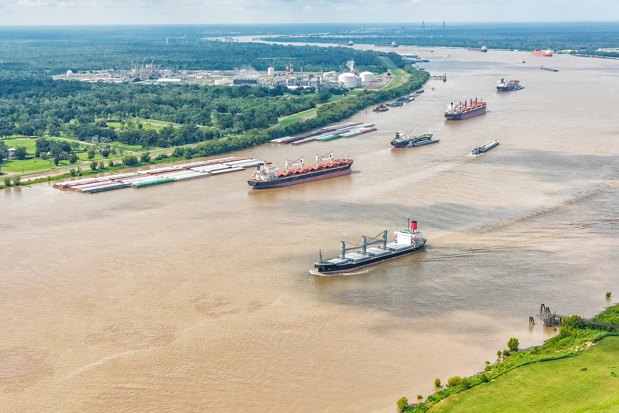 A variety of different cargo ships sailing along the Mississippi River near New Orleans