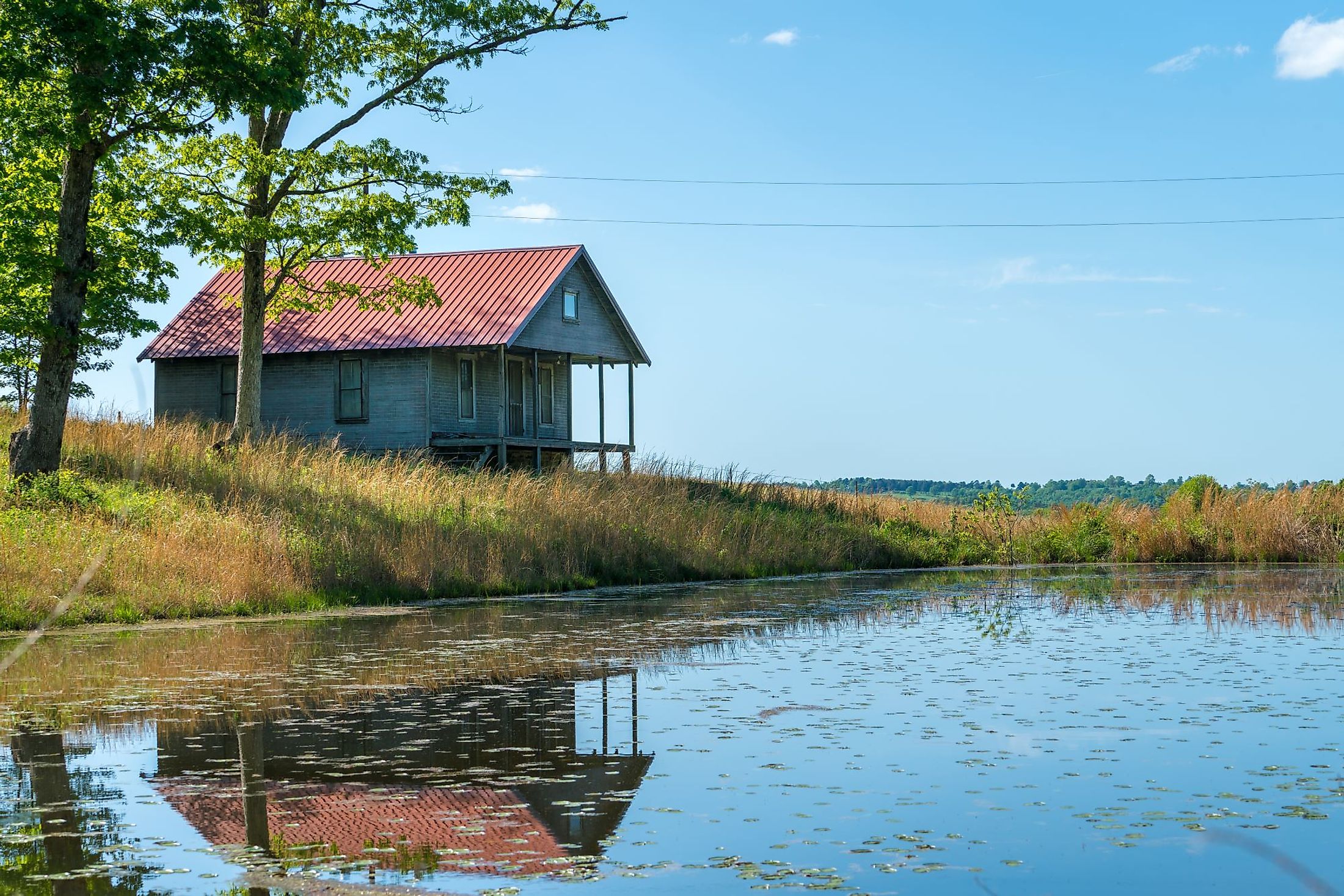 Rural old house barn reflected in pond water in northwest Arkansas, Ozark Mountains. 