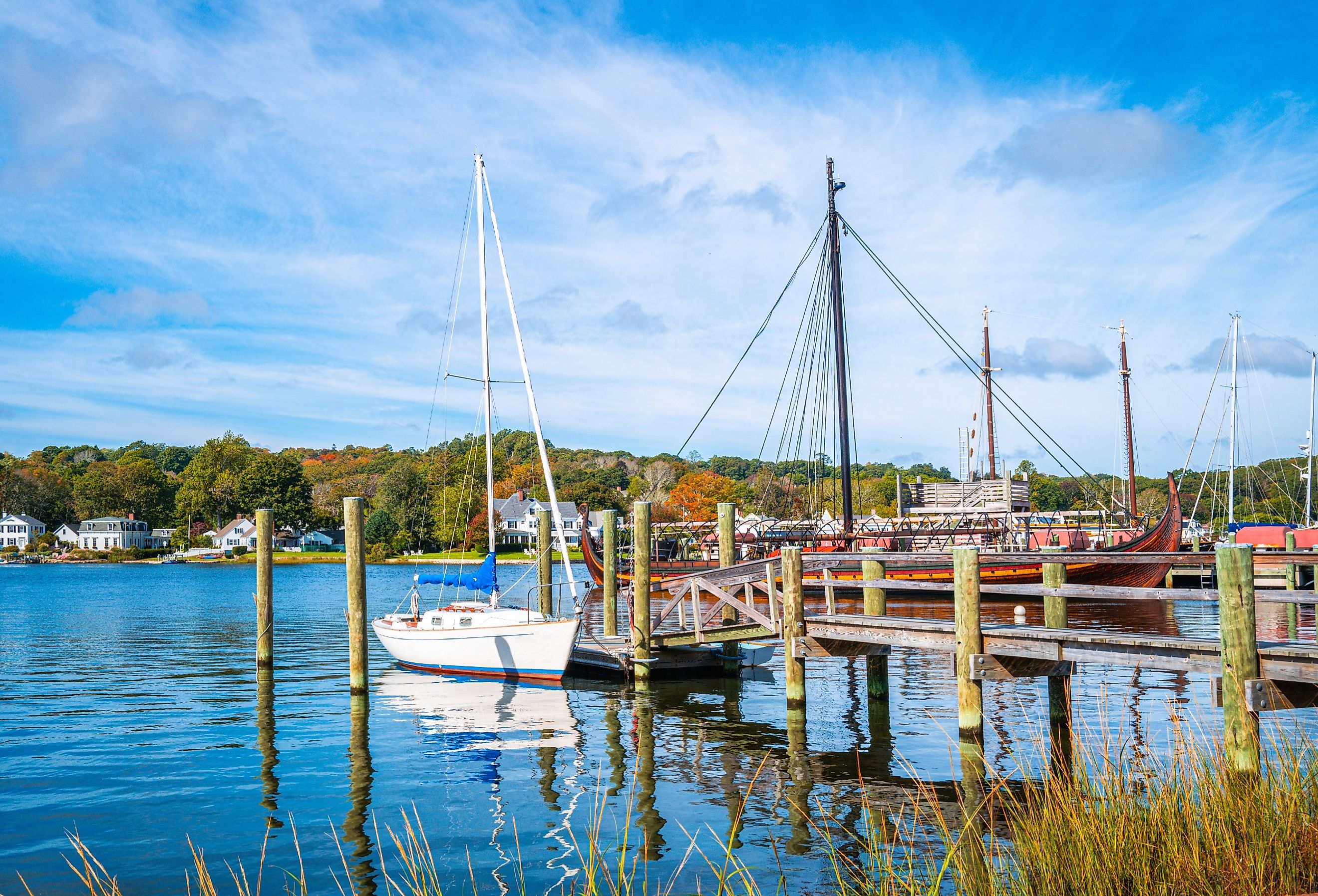 Commercial dock with moored white boat and sailing ship in Mystic, Connecticut.