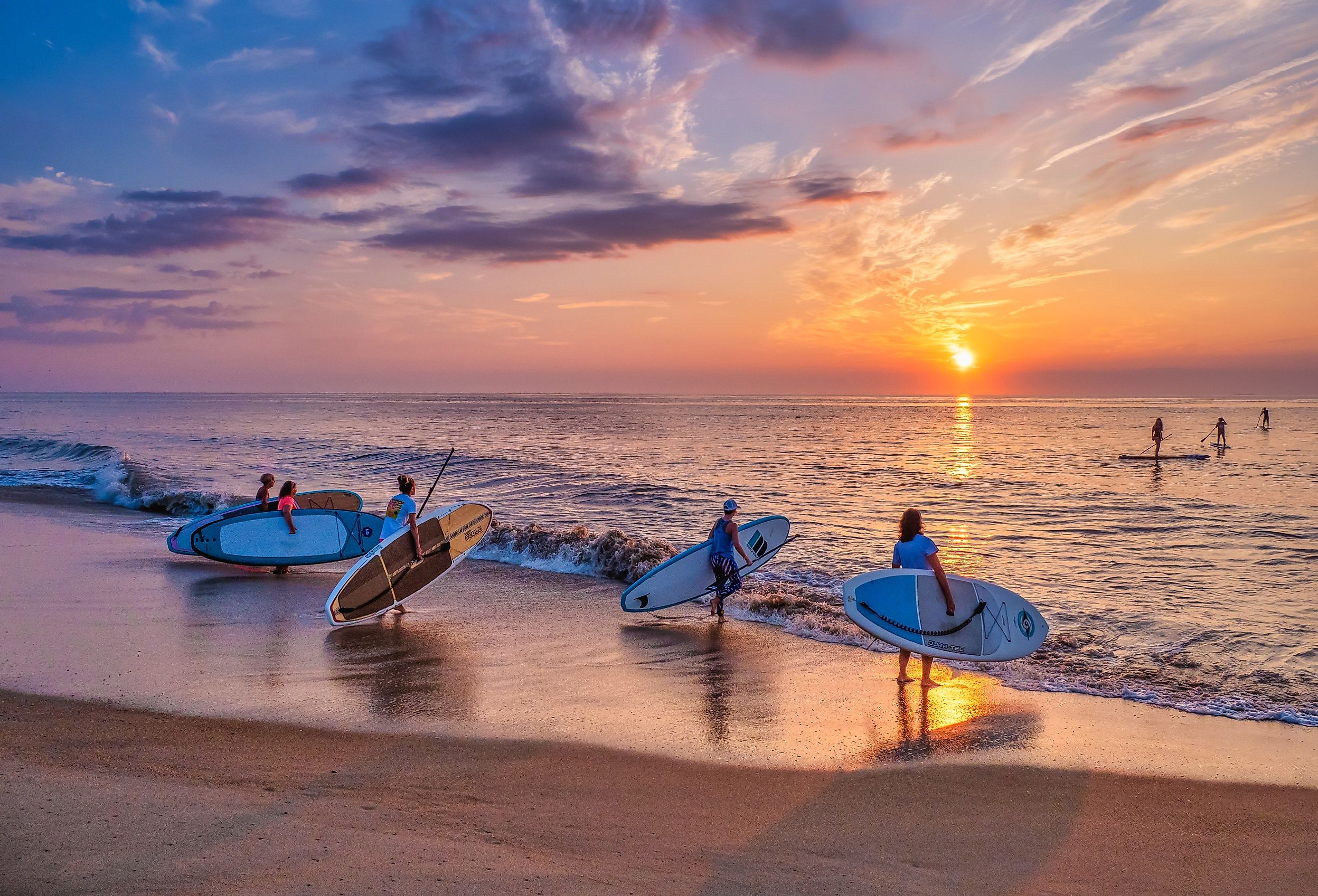 A group of outdoor enthusiasts take their paddle boards out at sunrise in Bethany Beach, Delaware.
