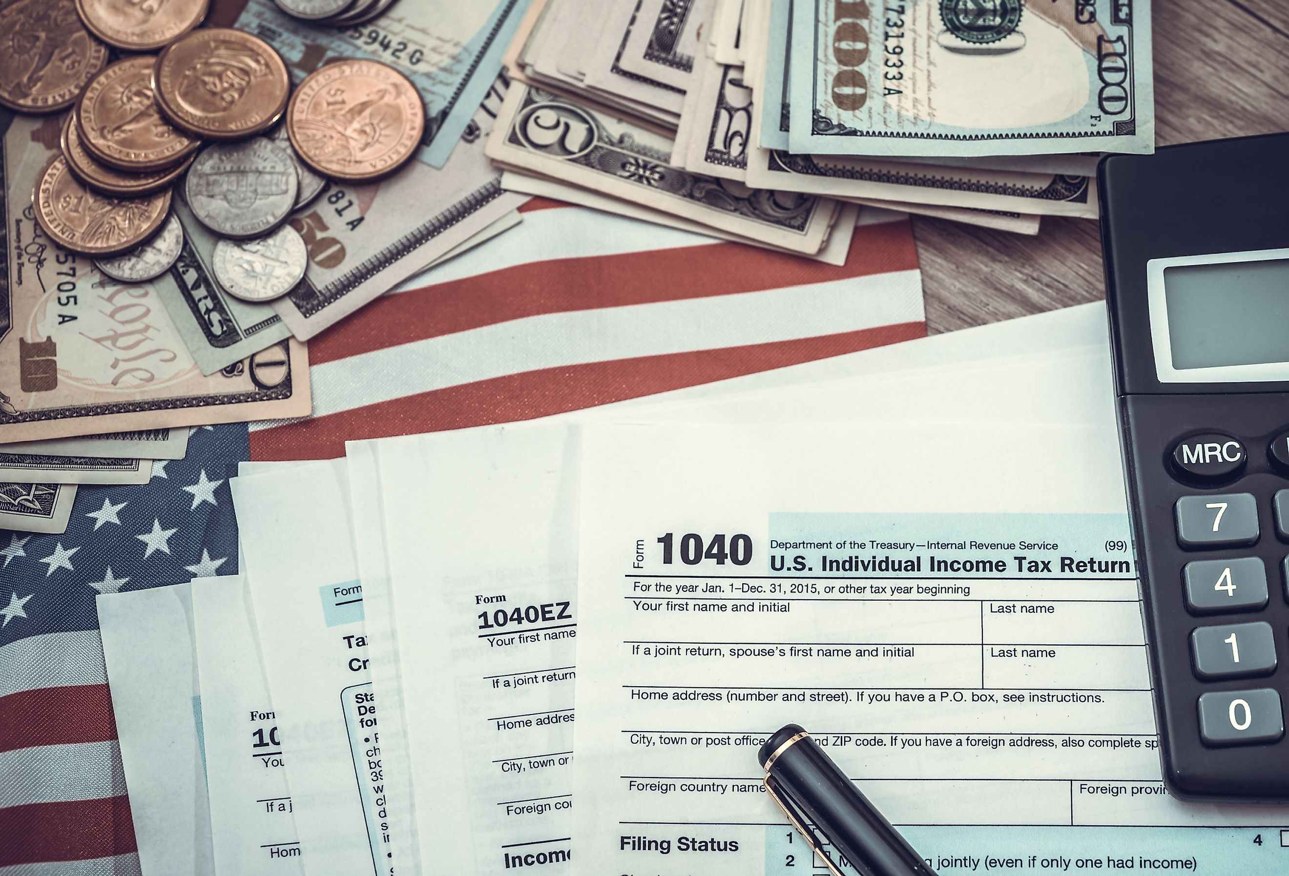 1040 tax form, pen, US money and flag.