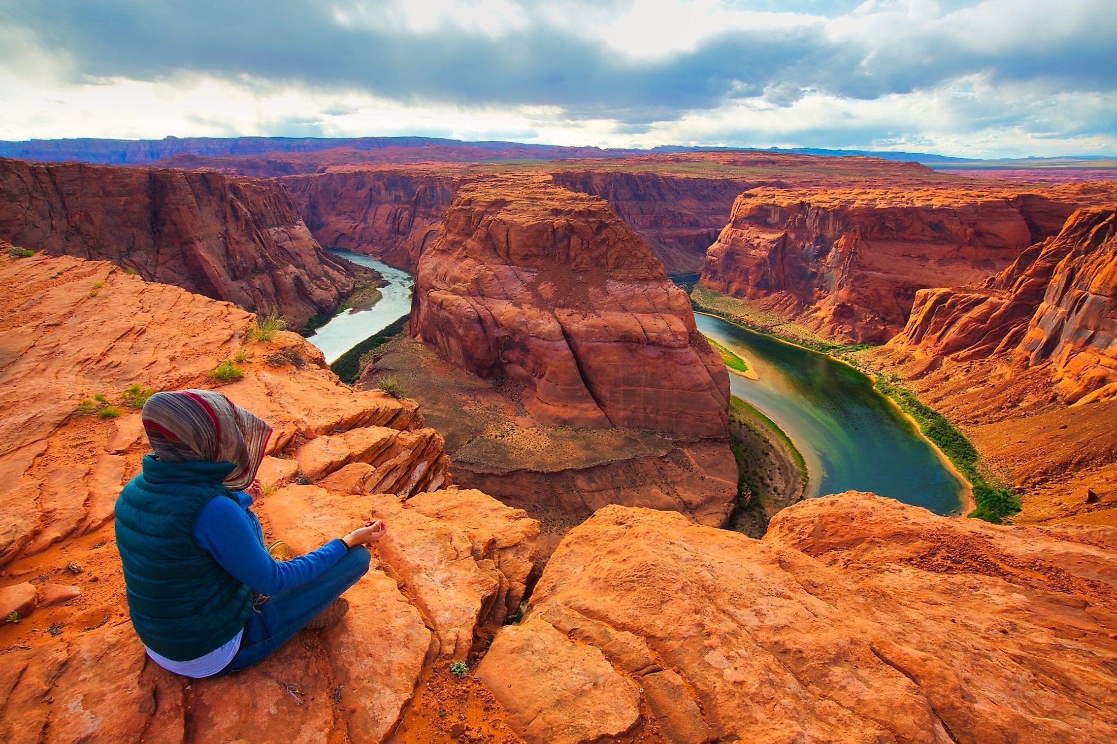 A person meditating in front of the scenic Horseshoe Bend of the Colorado River in Arizona.