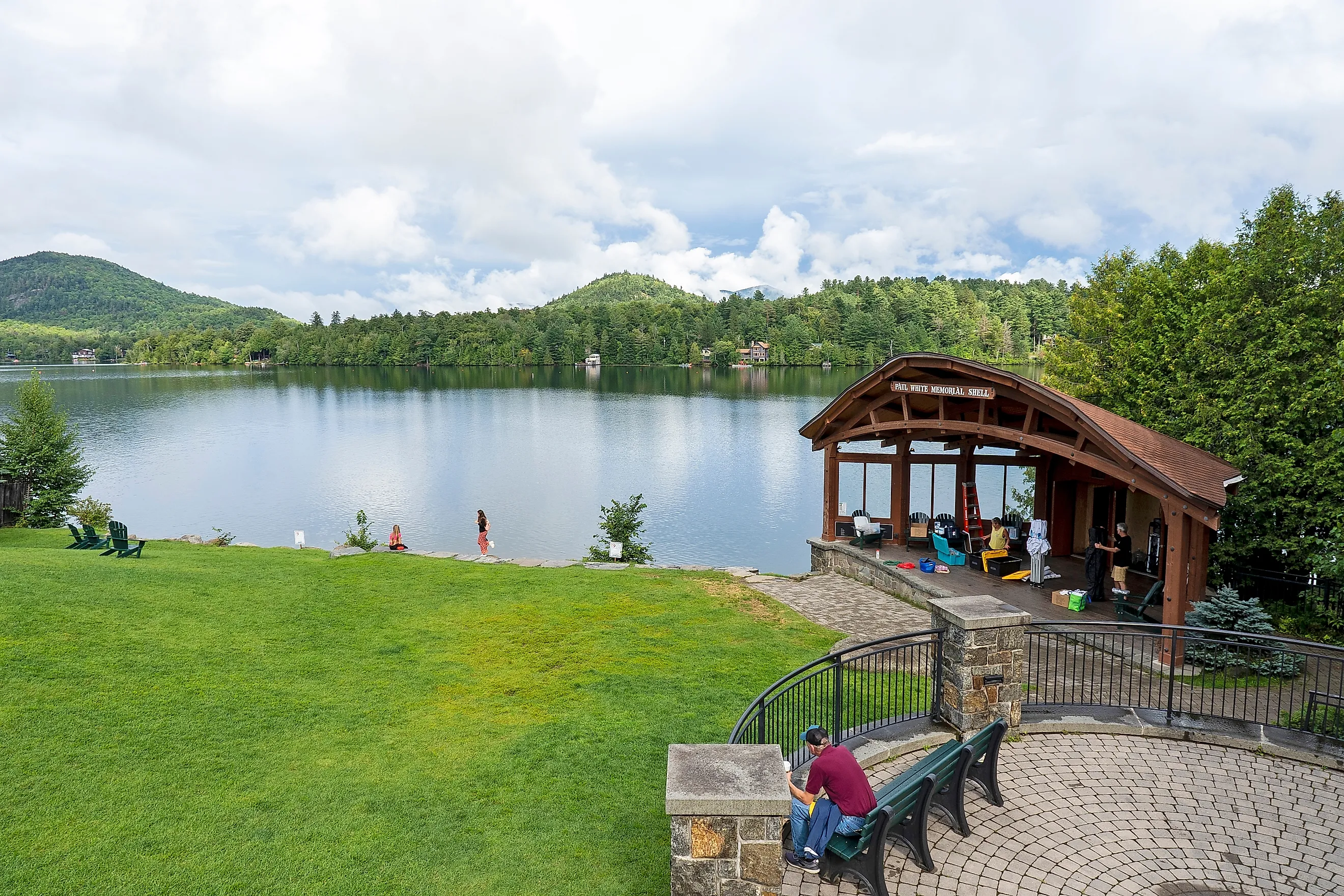 Tourists on lawn in front of Mirror Lake in Lake Placid, New York. Image credit: Catrina Genovese / Shutterstock.com.