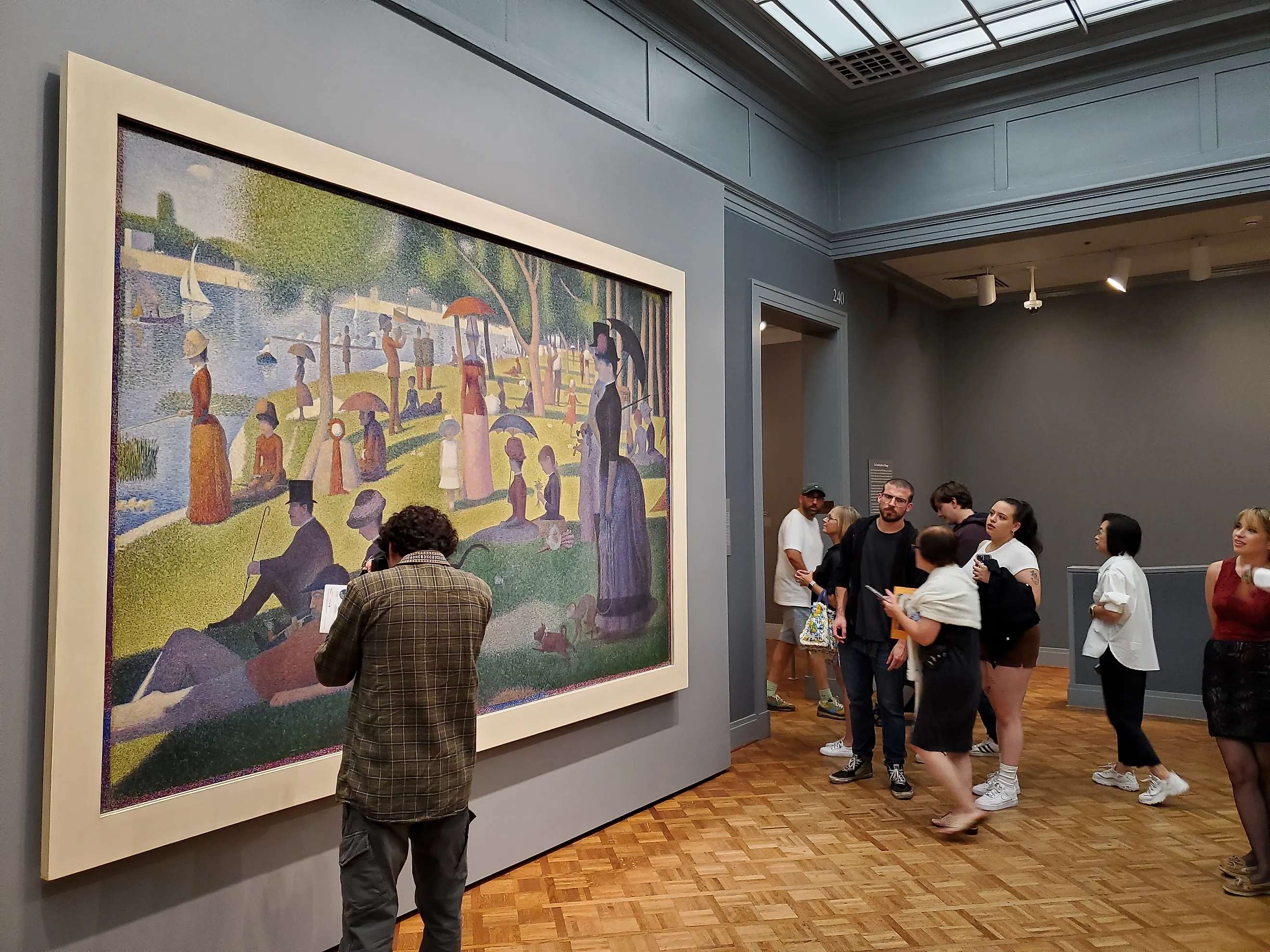 Chicago, IL, July 11, 2025, tourist standing in front of and looking at the painting A Sunday Afternoon on the Island of La Grande Jatte, on display at the Art Institute of Chicago, Georges Seurat. Editorial Photo Credit:ChicagoPhotographer Shutterstock. 