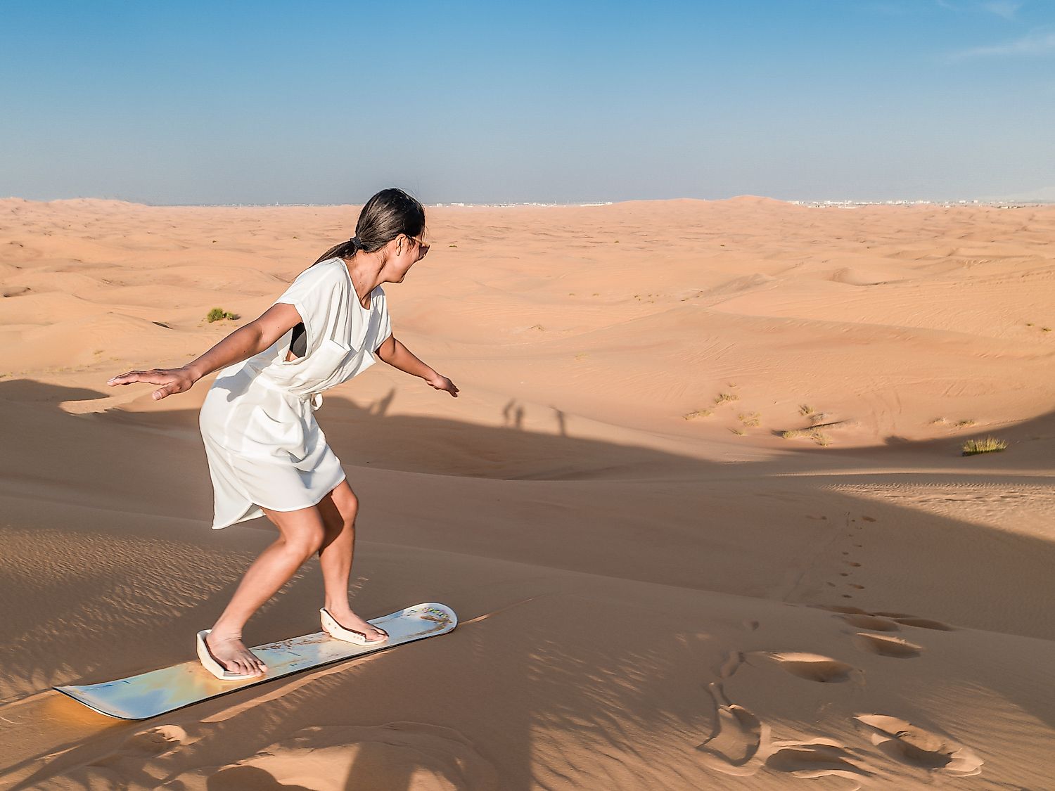 Young woman sand boarding in the desert over the sand dunes. Image credit: Fokke Baarssen/Shutterstock.com