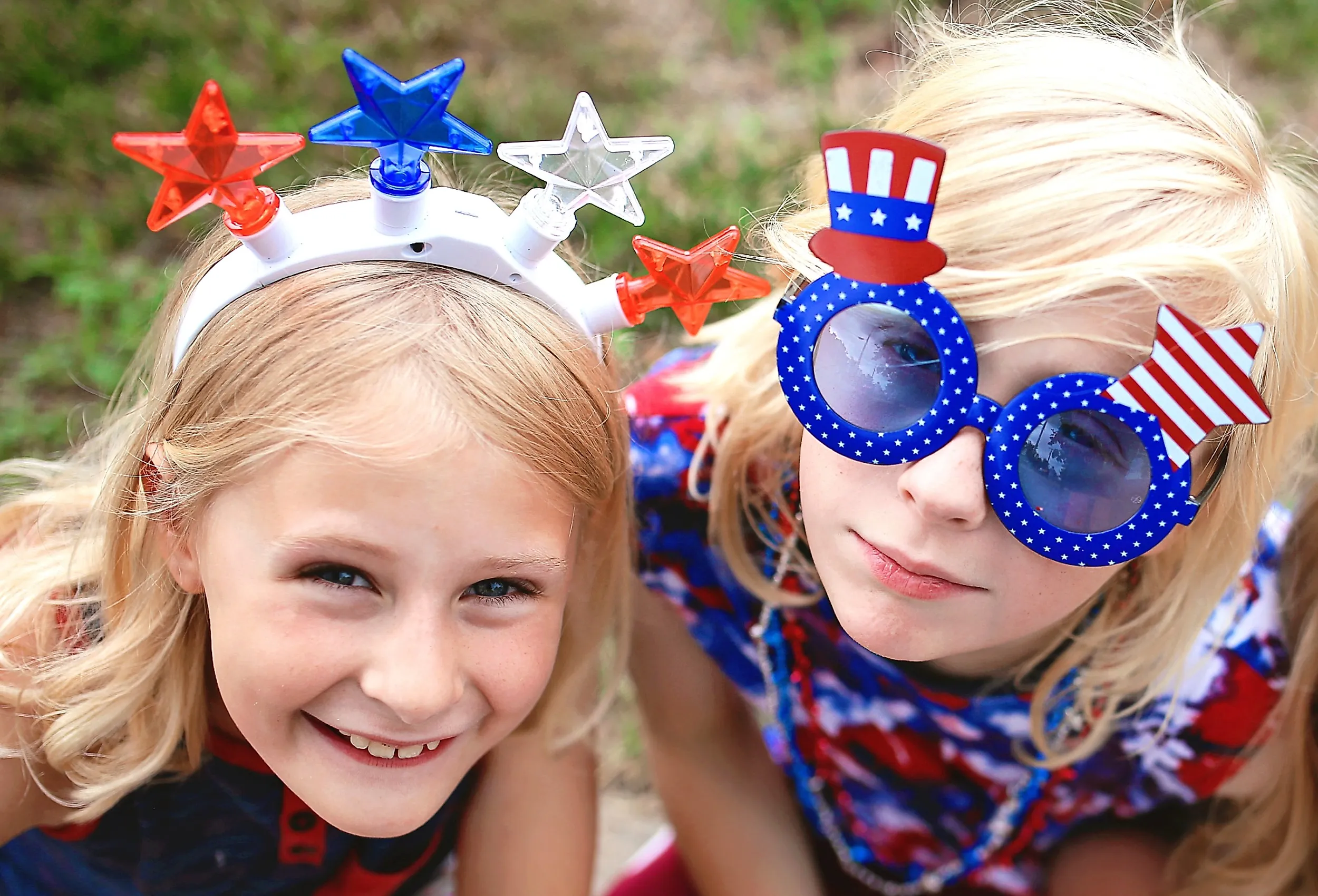 Two Patriotic little kids are sitting at a Fourth of July parade in a small town in America.