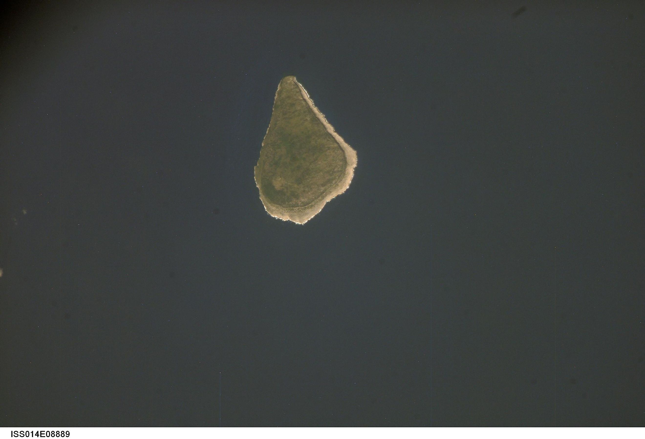 Astronaut photo of teardrop-shaped Navassa Island. The island is basically a plateau encircled by fairly steep cliffs.