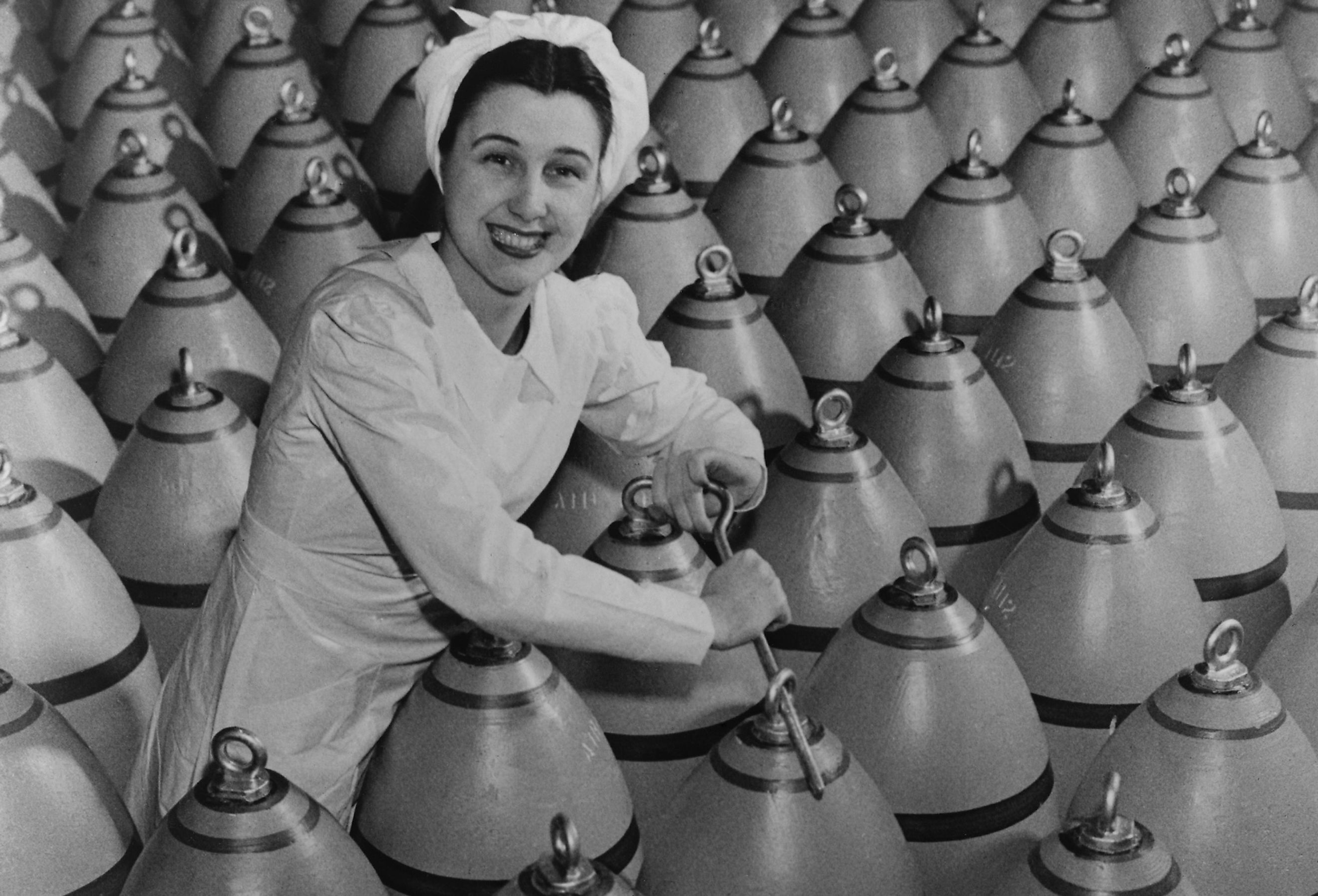 Canadian woman munitions worker tightening the nose plugs on 500-pound aerial bombs.