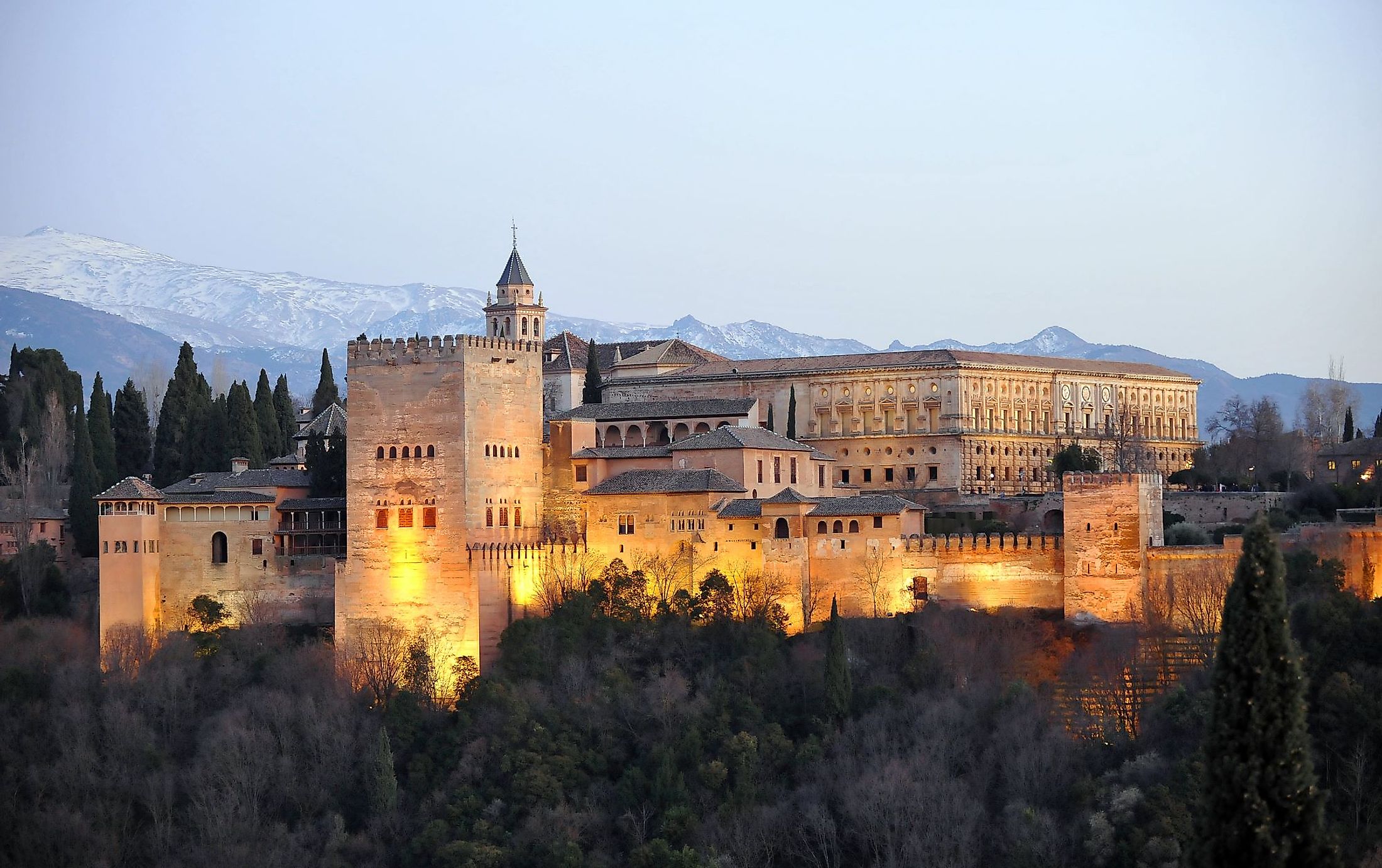 The Palace of Alhambra with Comares Tower, Palace of Charles V and Sierra Nevada at the background during sunset in Granada, Andalusia, Spain. 